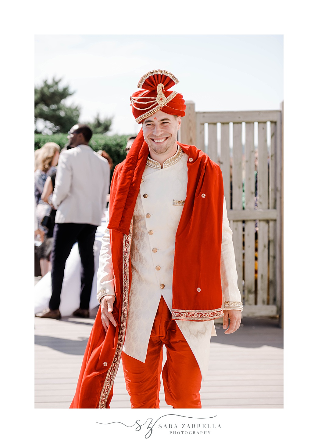 groom in red turban and wrap walks down aisle for traditional Indian wedding ceremony at Newport Beach House