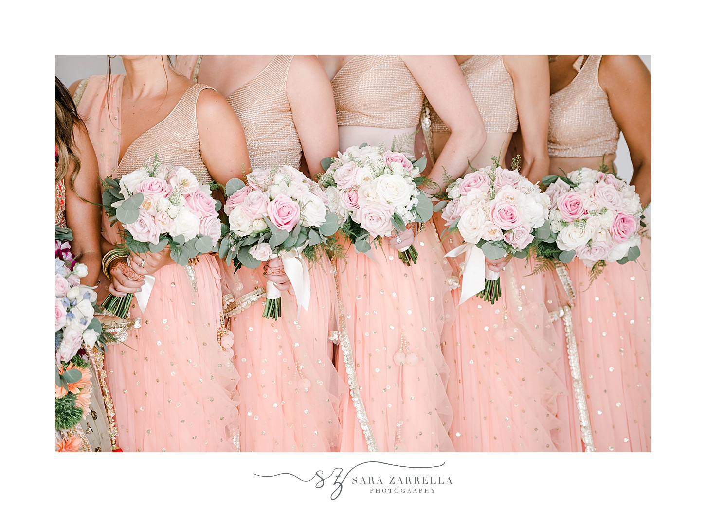 bridesmaids in pale pink saris hold flowers
