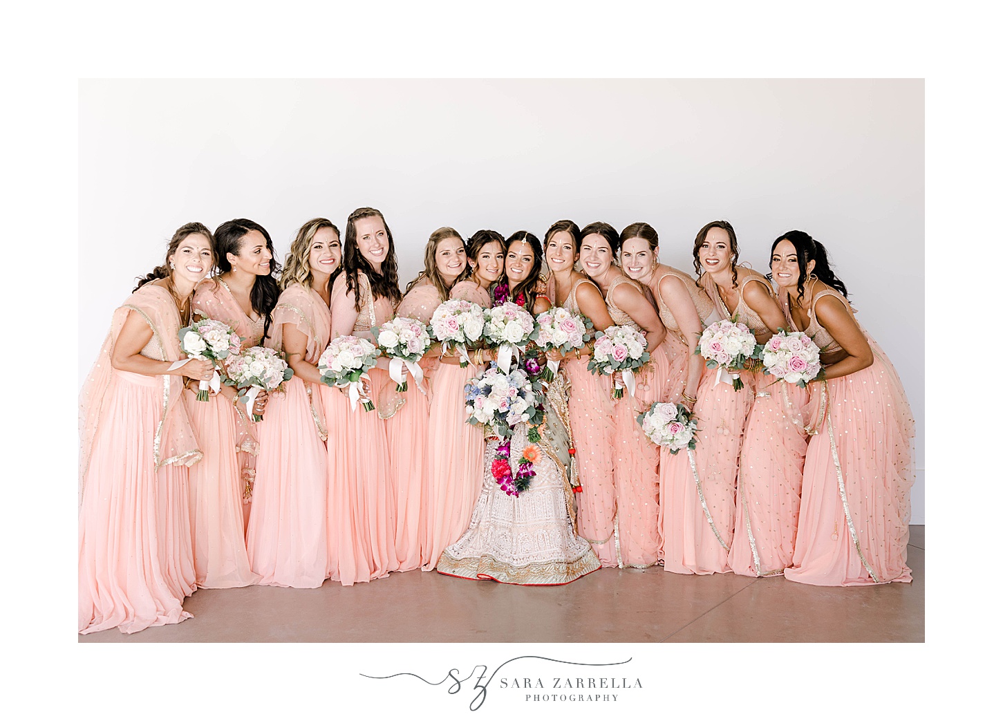 bride and bridesmaids in pink saris hug together in Newport Beach House