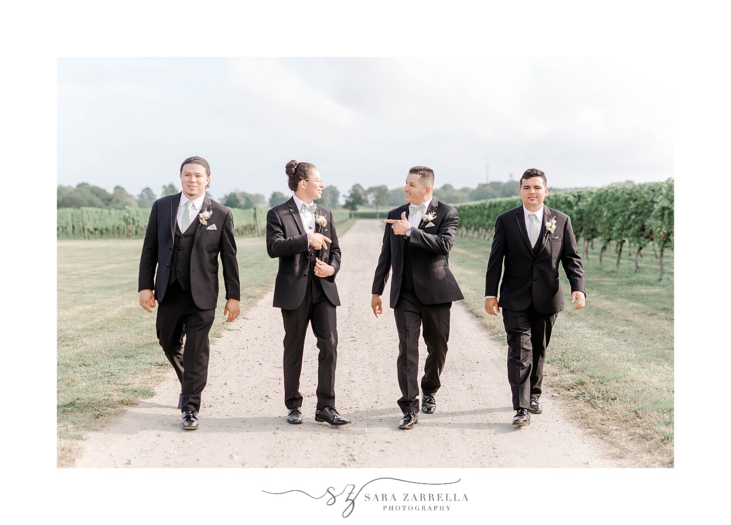 groom walks with three groomsmen on path at Newport Vineyards