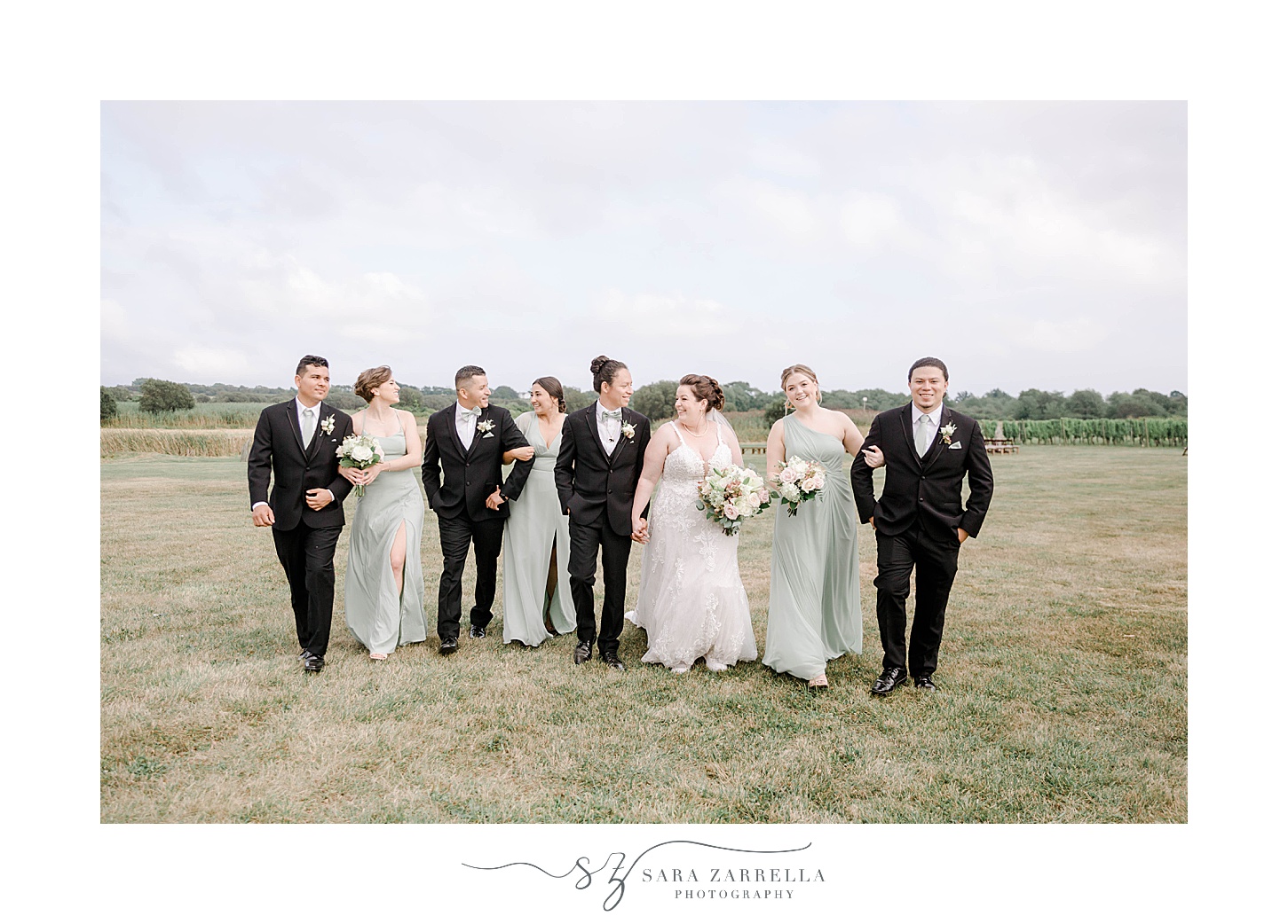 newlyweds walk with wedding party in mint green dresses and black suits at Newport Vineyards