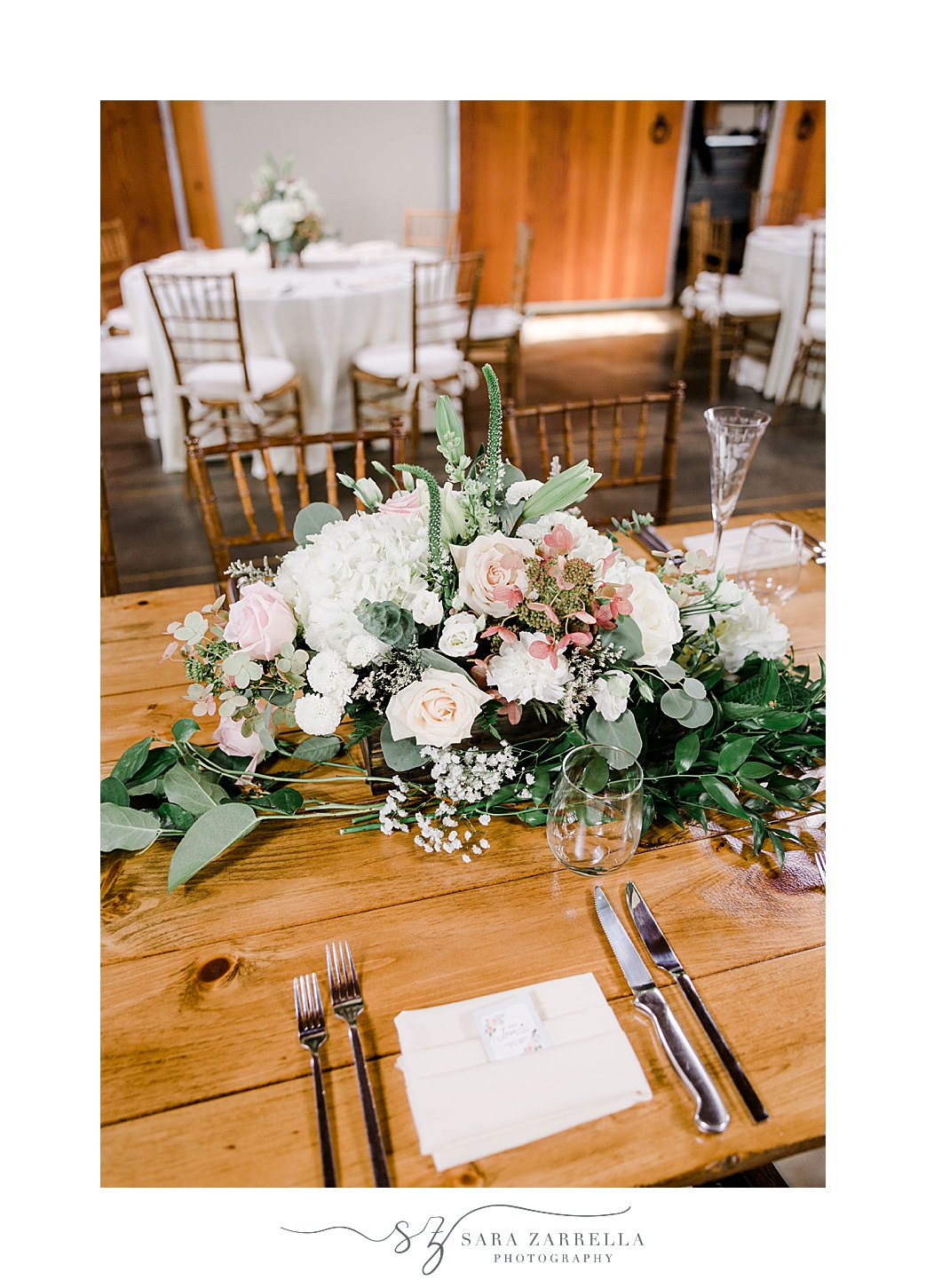 place setting with pink and white floral centerpiece on wooden table