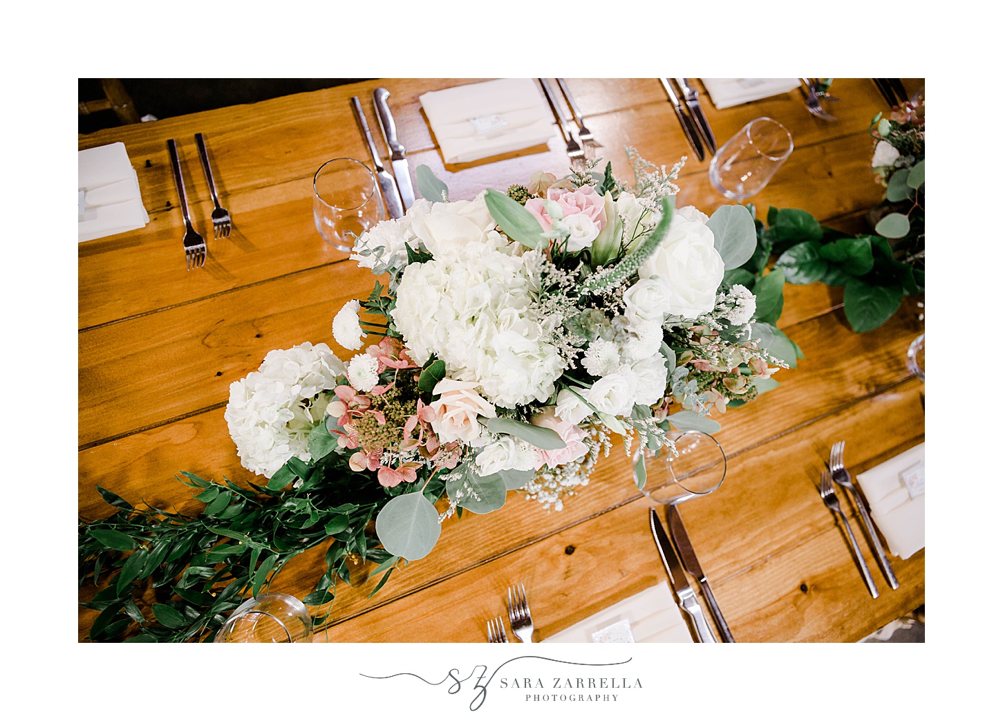 white and pink floral centerpiece at Newport Vineyards on wooden tables
