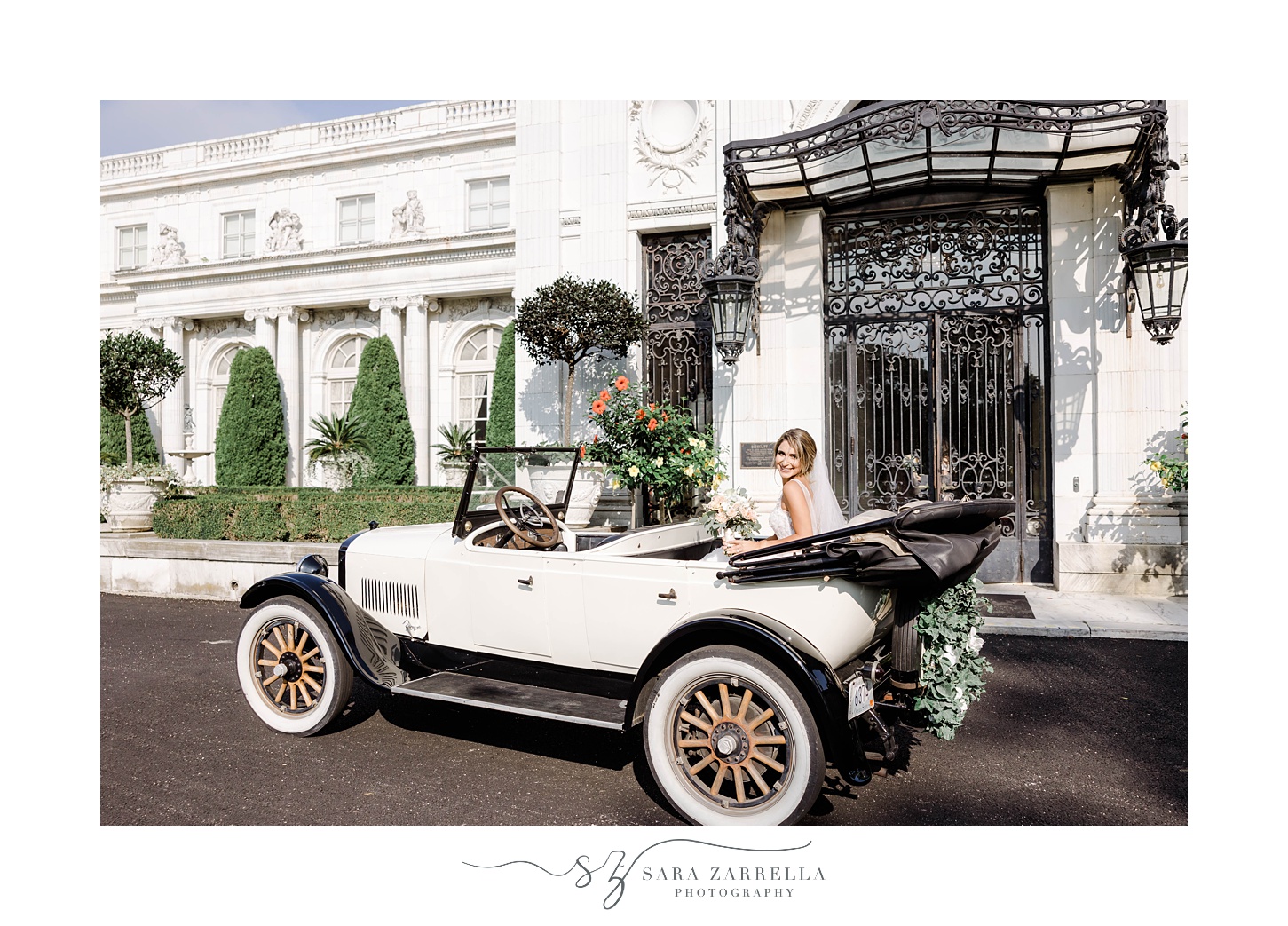 bride sits in back of classic car outside Rosecliff Mansion