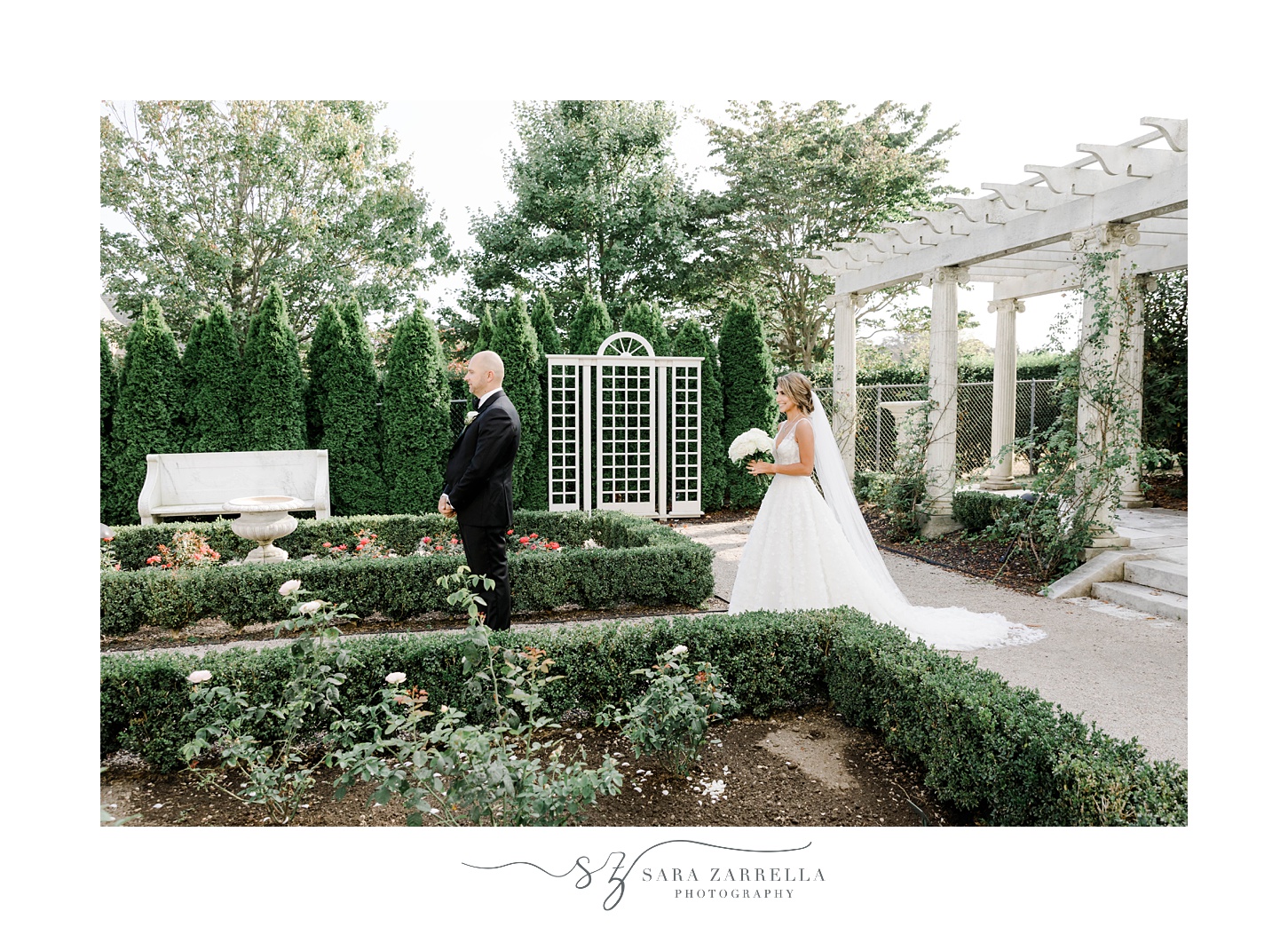 bride approaches groom between hedges in garden at Rosecliff Mansion