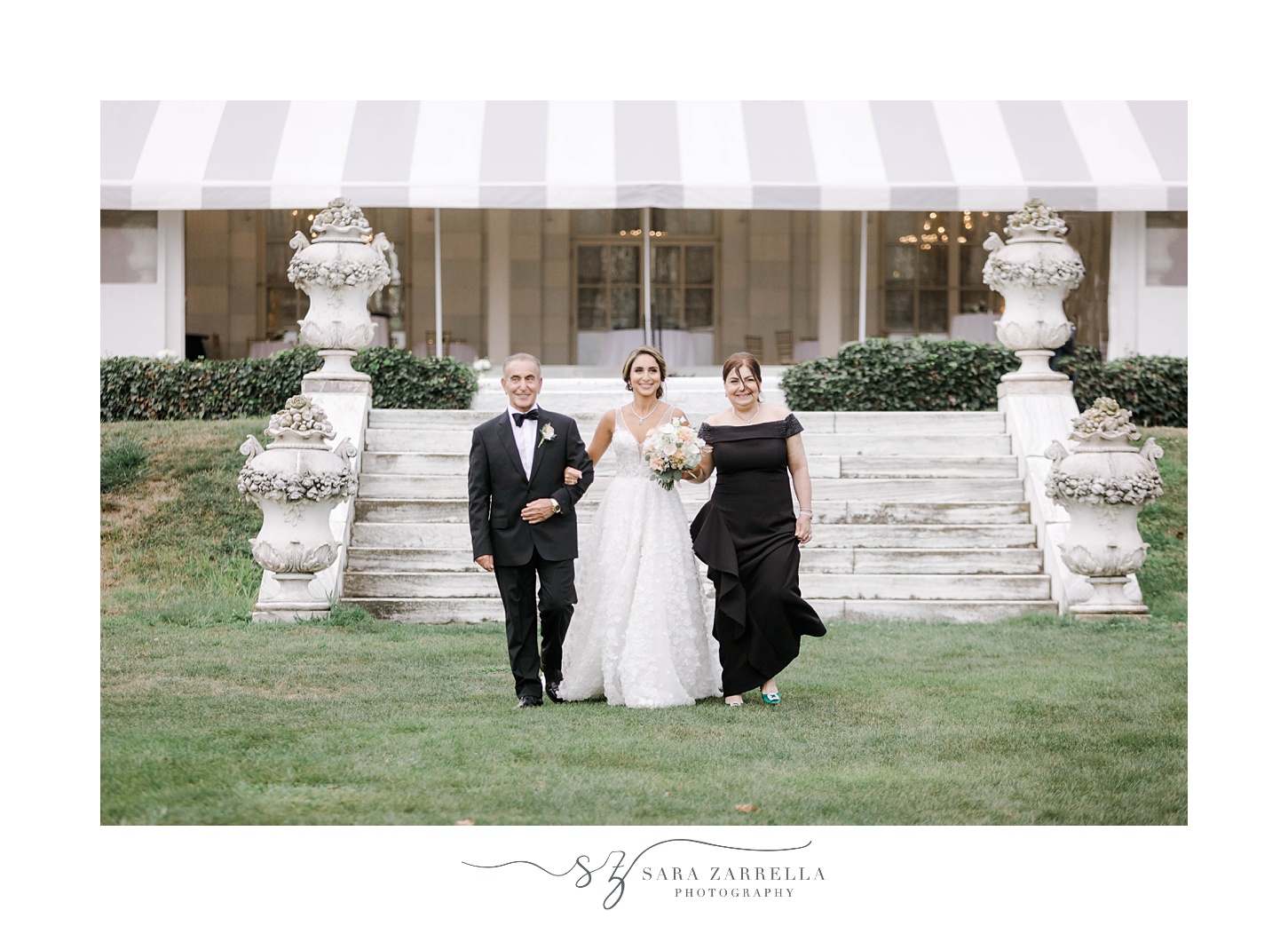 bride walks with parents down aisle at Rosecliff Mansion