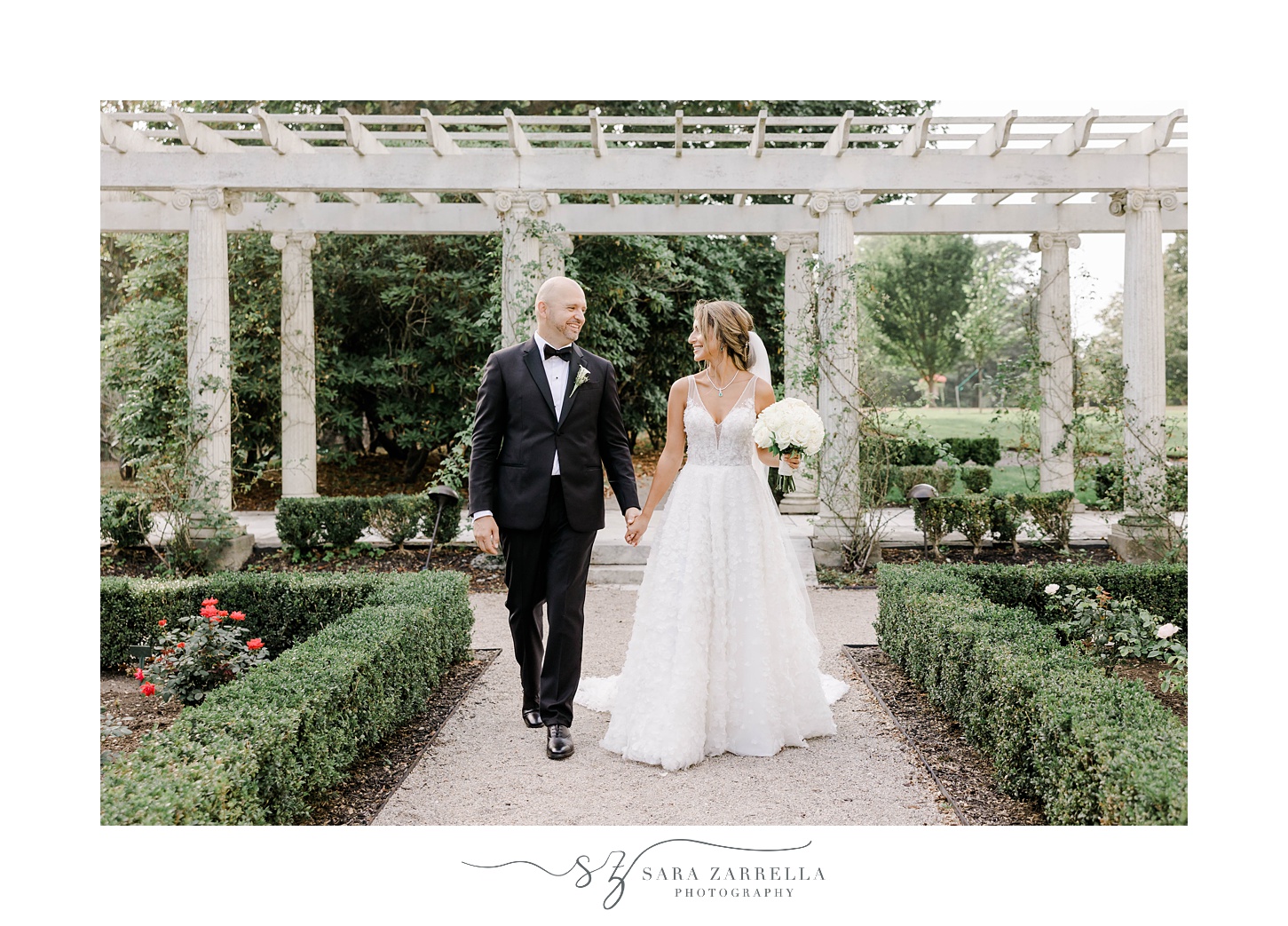 bride and groom walk together through garden at Rosecliff Mansion