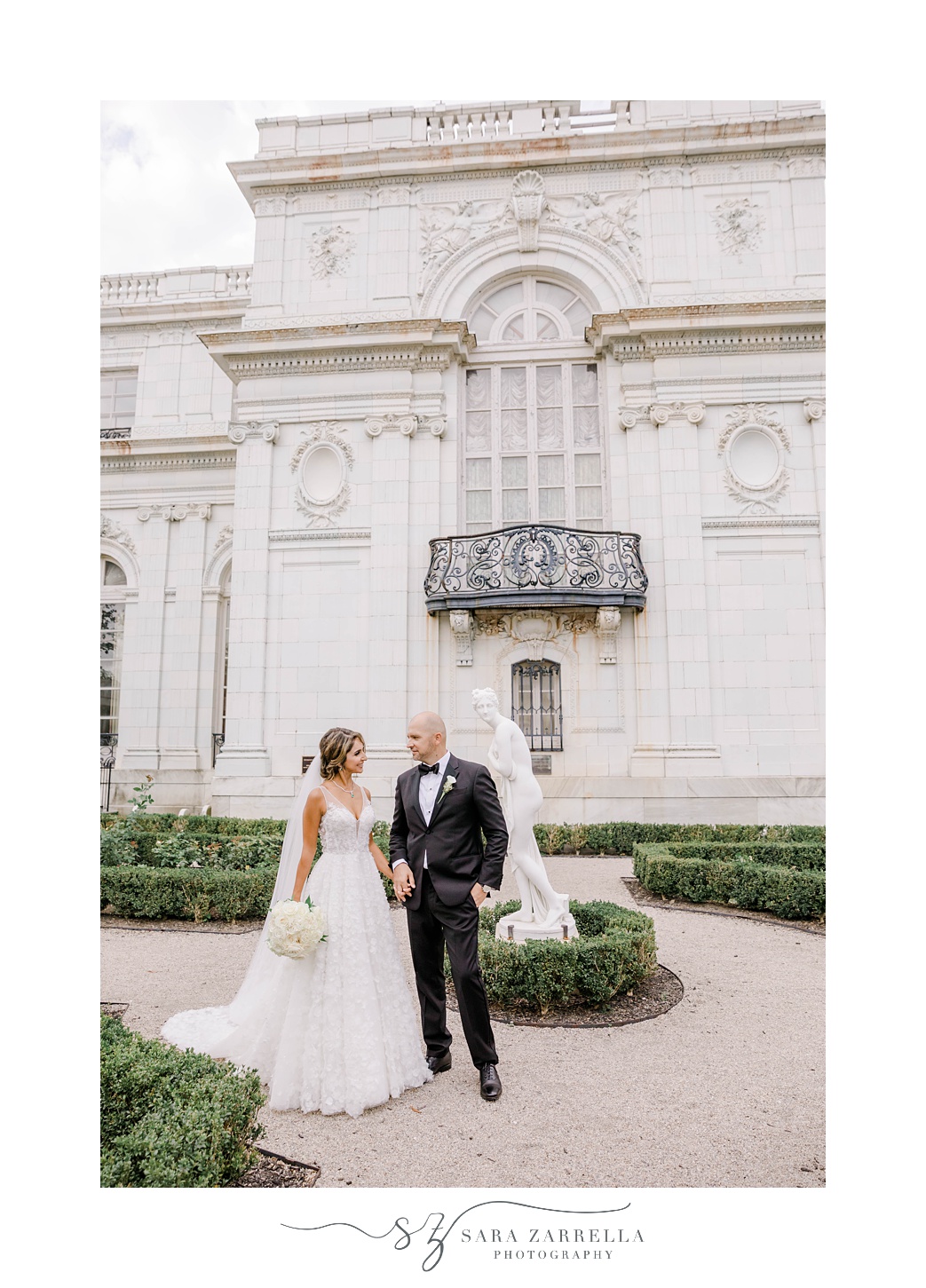 bride and groom pose by statue at Rosecliff Mansion
