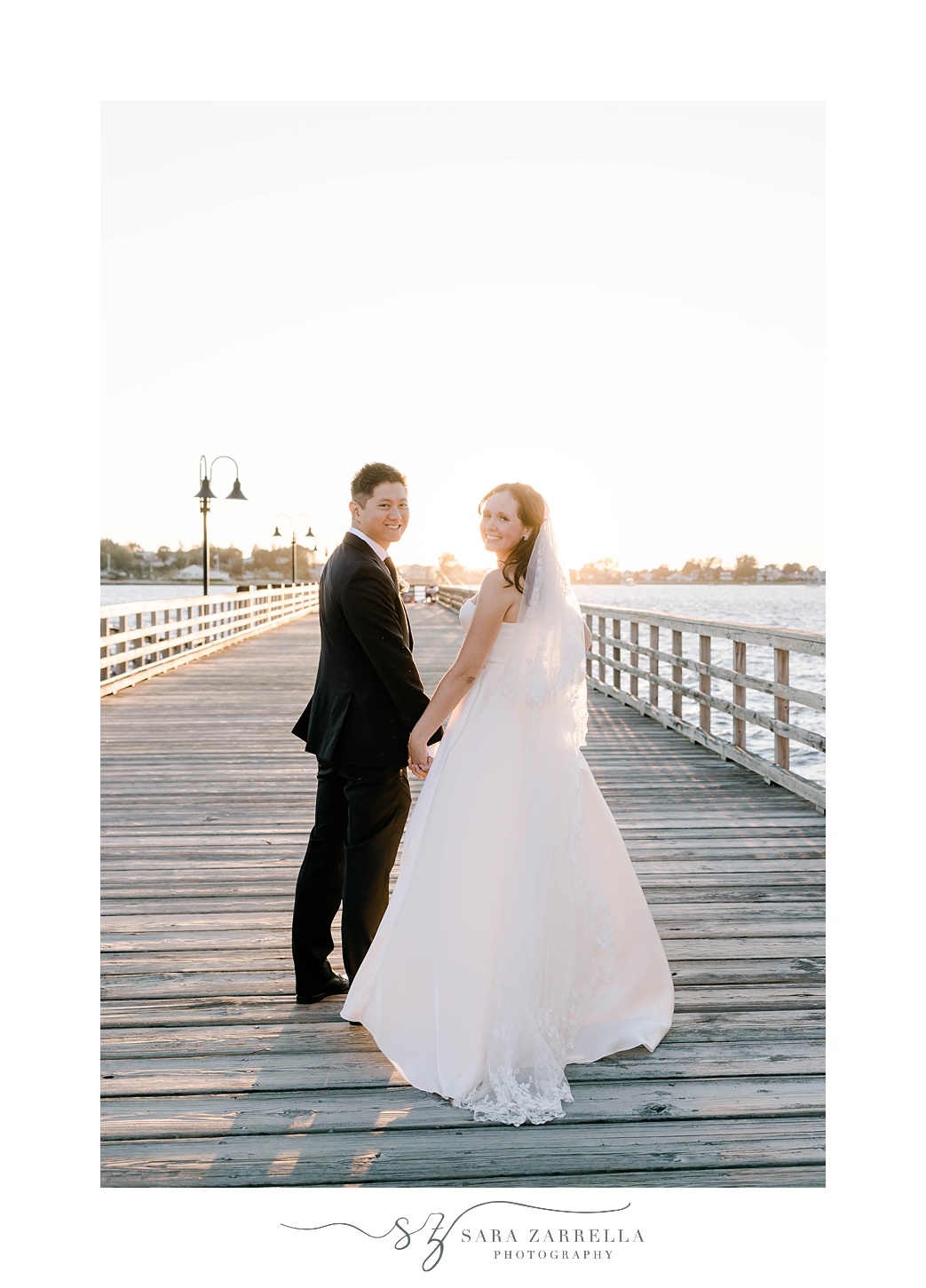 bride and groom hold hands on dock at The Boat House