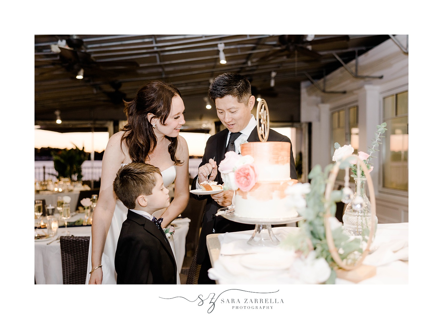 son looks at wedding cake with parents at The Boat House