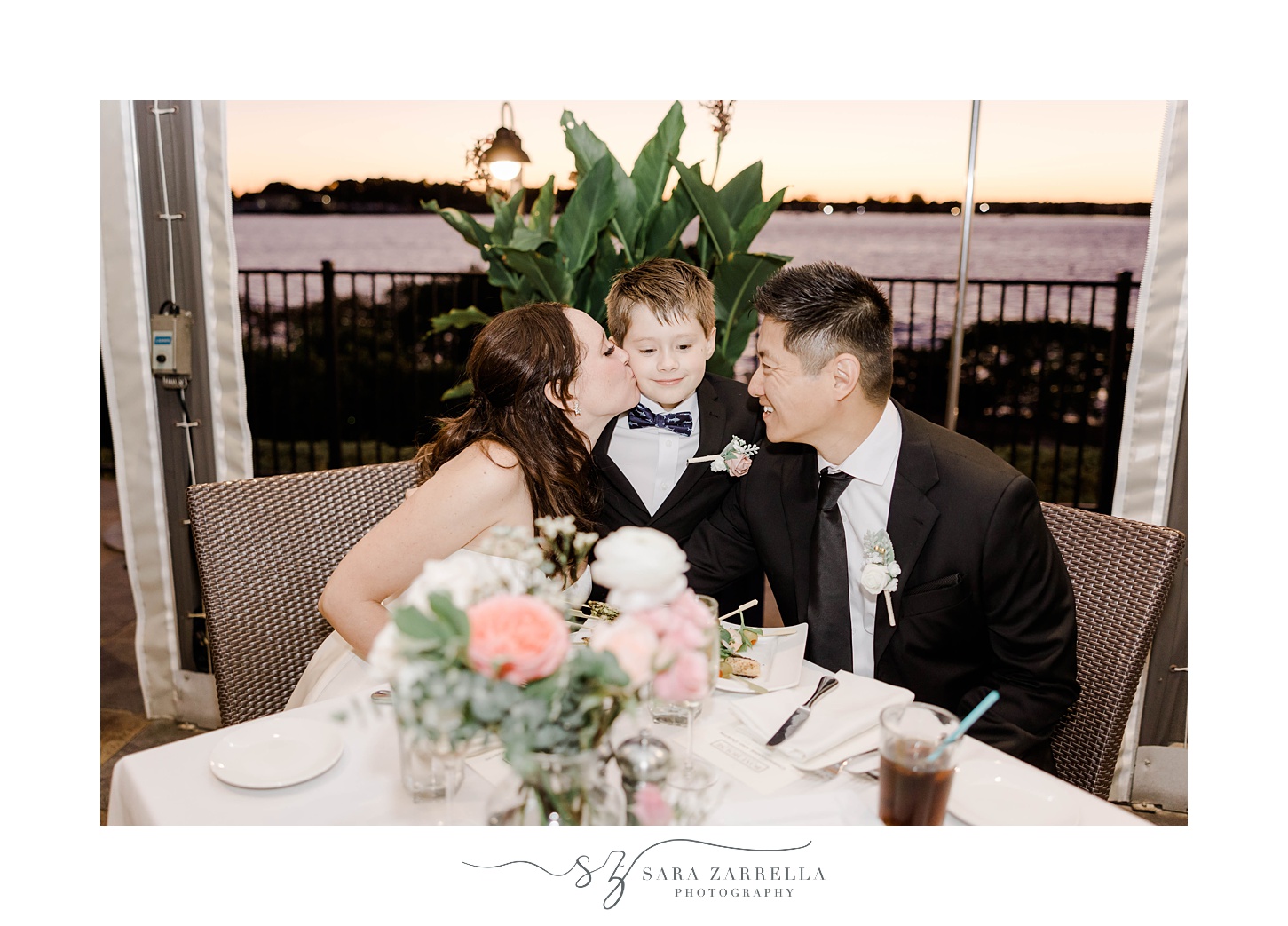 bride and groom kiss son's cheeks during reception at The Boat House