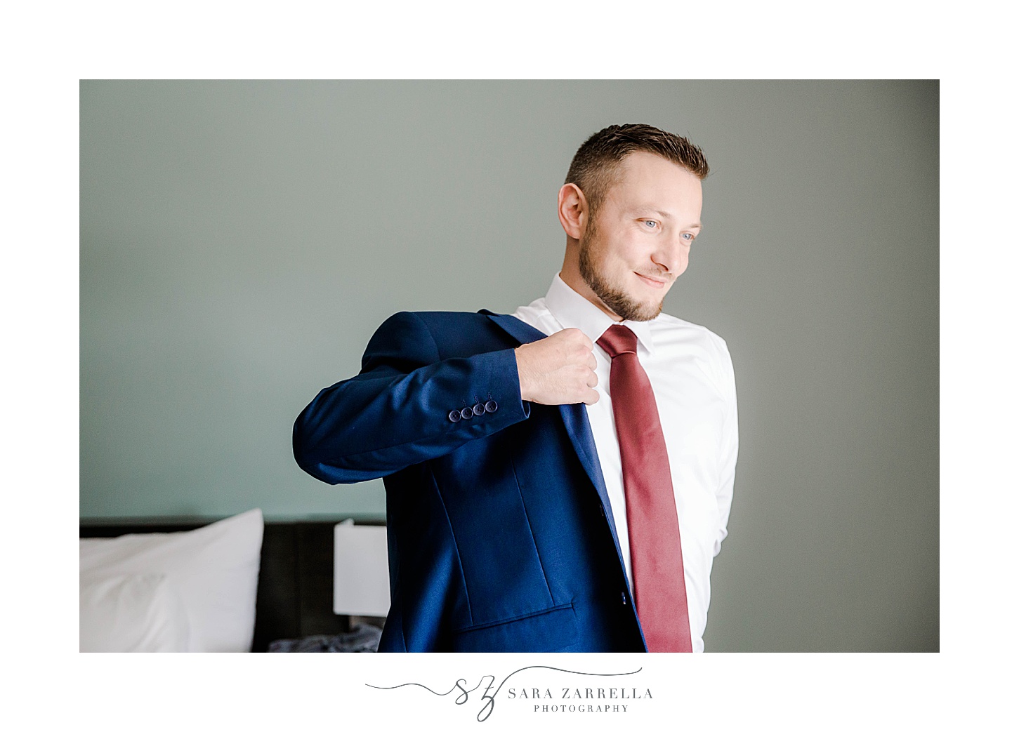 groom puts on navy jacket with red tie
