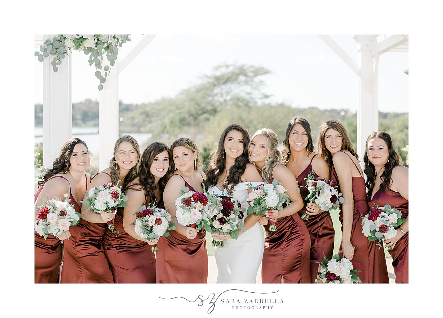 bridesmaids in burgundy gowns hug bride during Atlantic Resort Wyndham wedding photos 