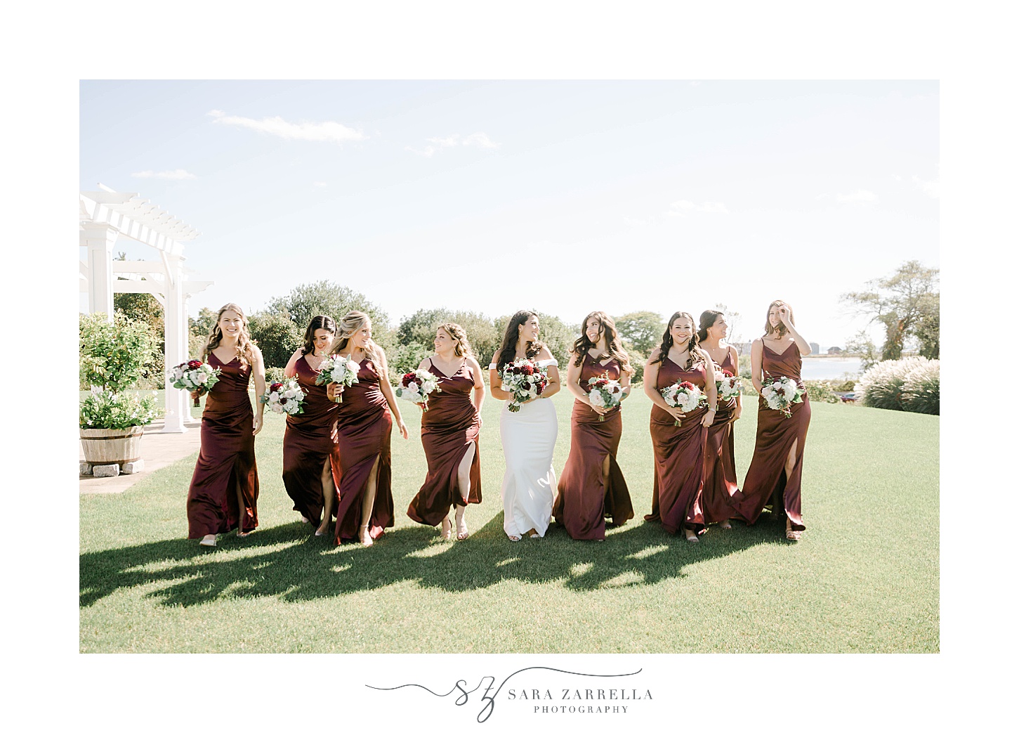 bride walks with bridesmaids in red gowns 