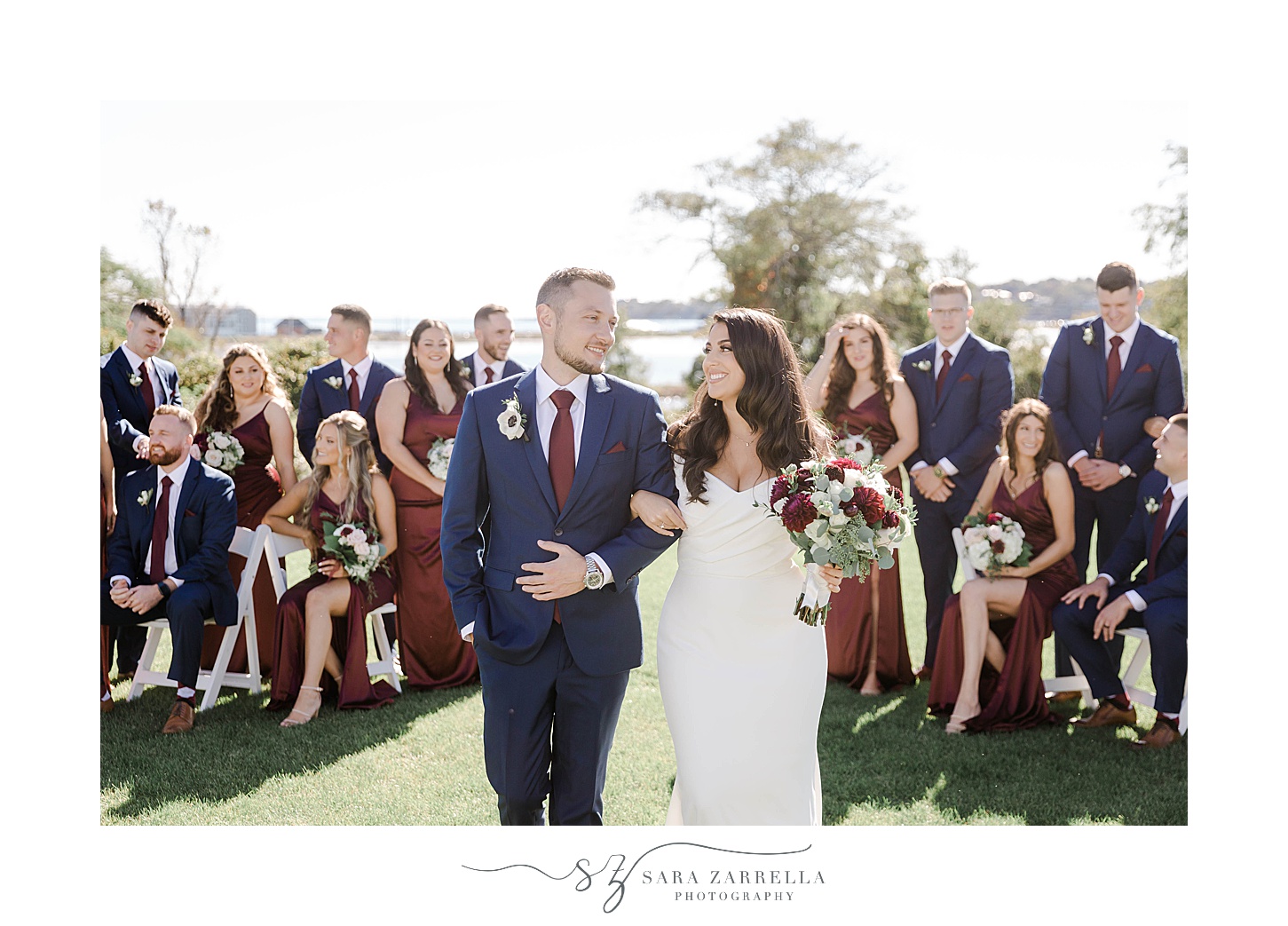 bride and groom walk in front of wedding party in navy and burgundy