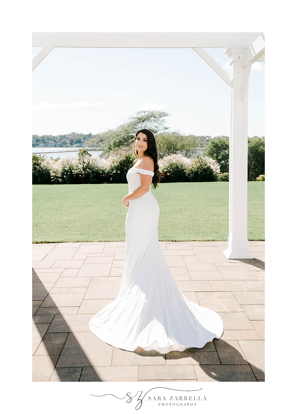 bride stands in off-the- shoulder sleek wedding gown