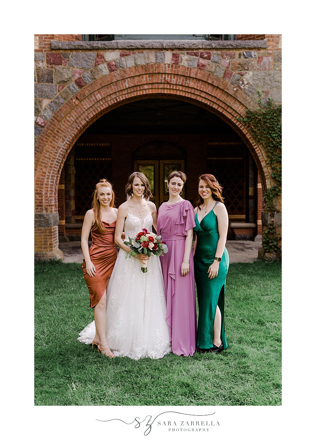 bride poses with bridesmaids in jewel tone gowns