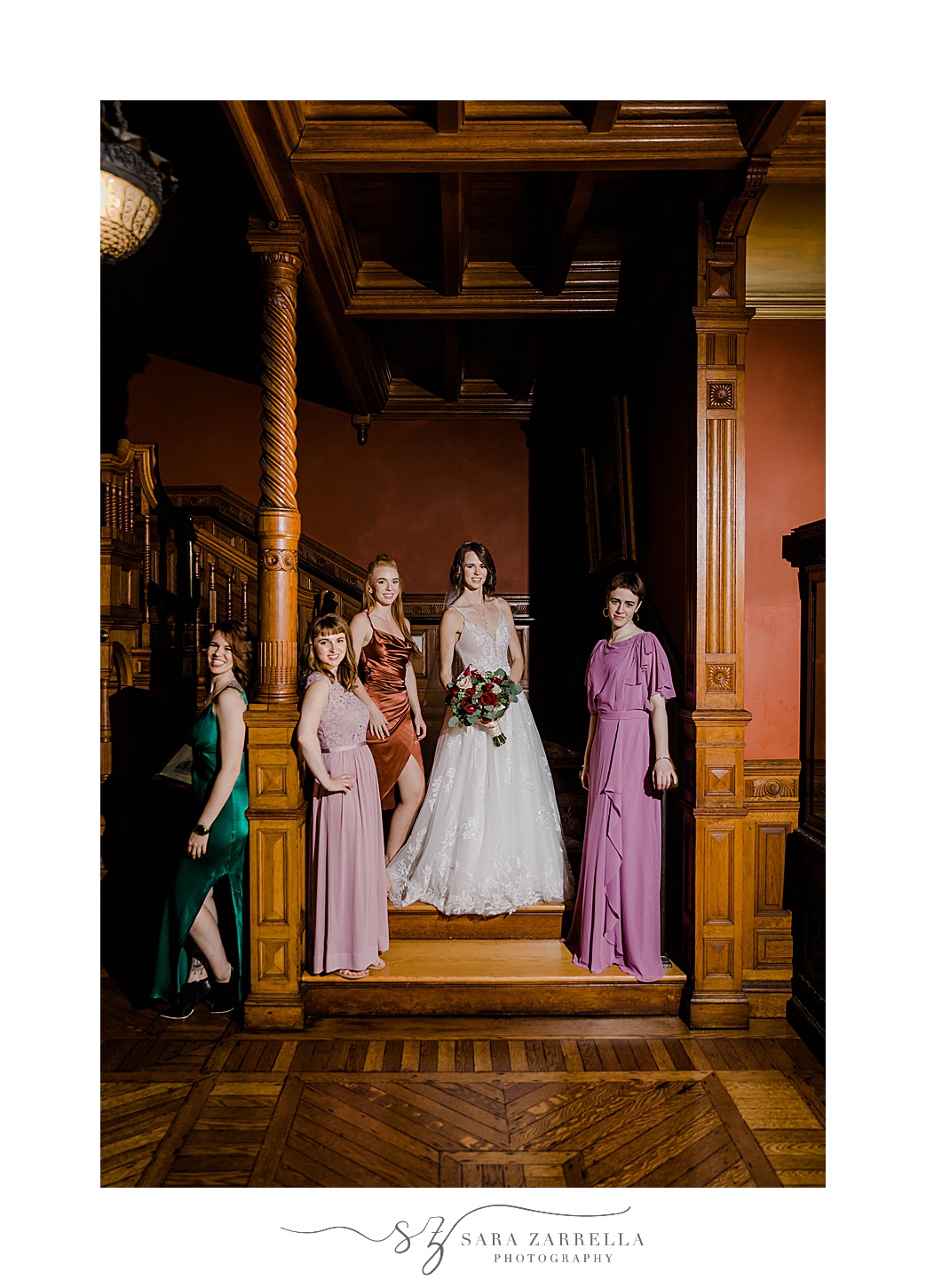 bride and bridesmaids pose on staircase inside Eustis Estate