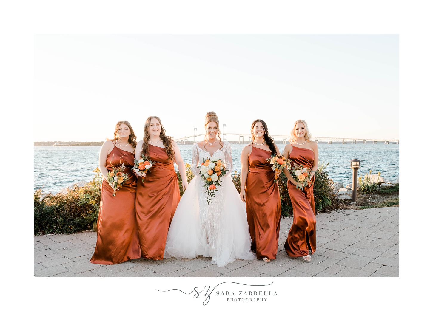 bride walks with bridesmaids in orange gowns outside Newport Harbor Island Resort