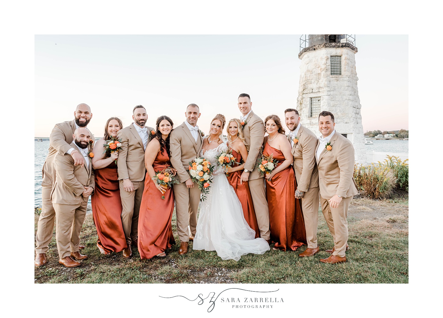 bride and groom pose with wedding party outside Newport Lighthouse 