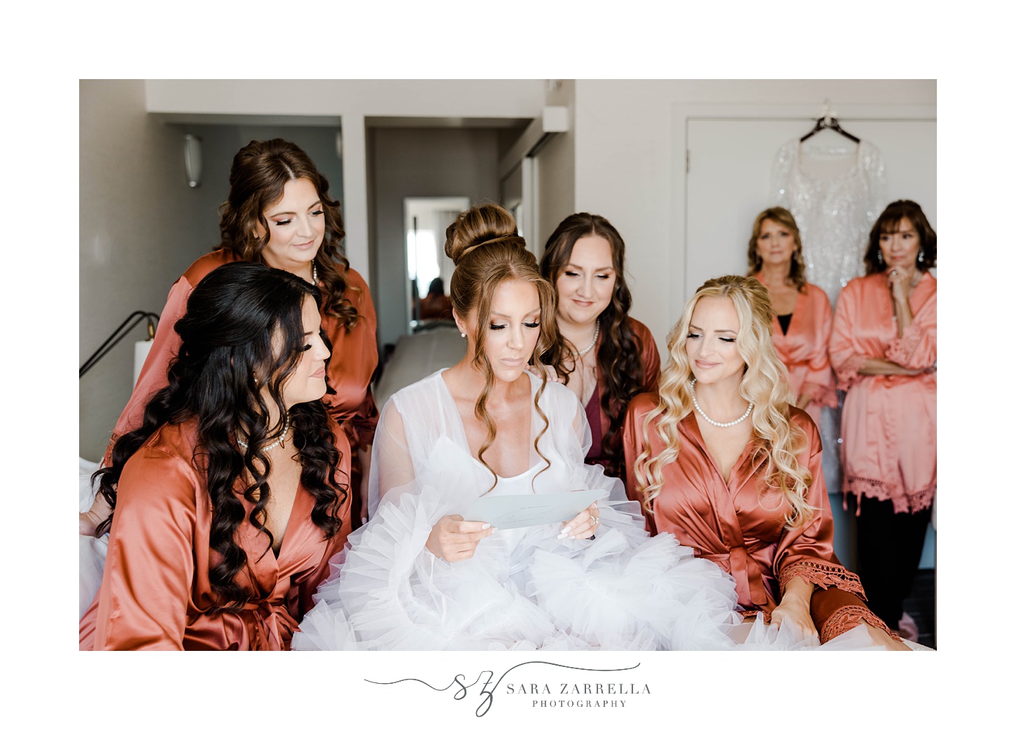 bride reads letter surrounded by bridesmaids in orange robes 