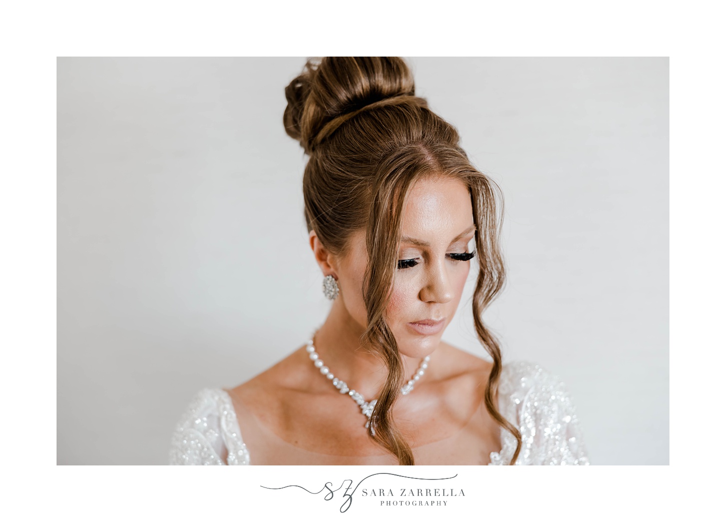 bride looks down at floor showing off bun and tendrils of hair 