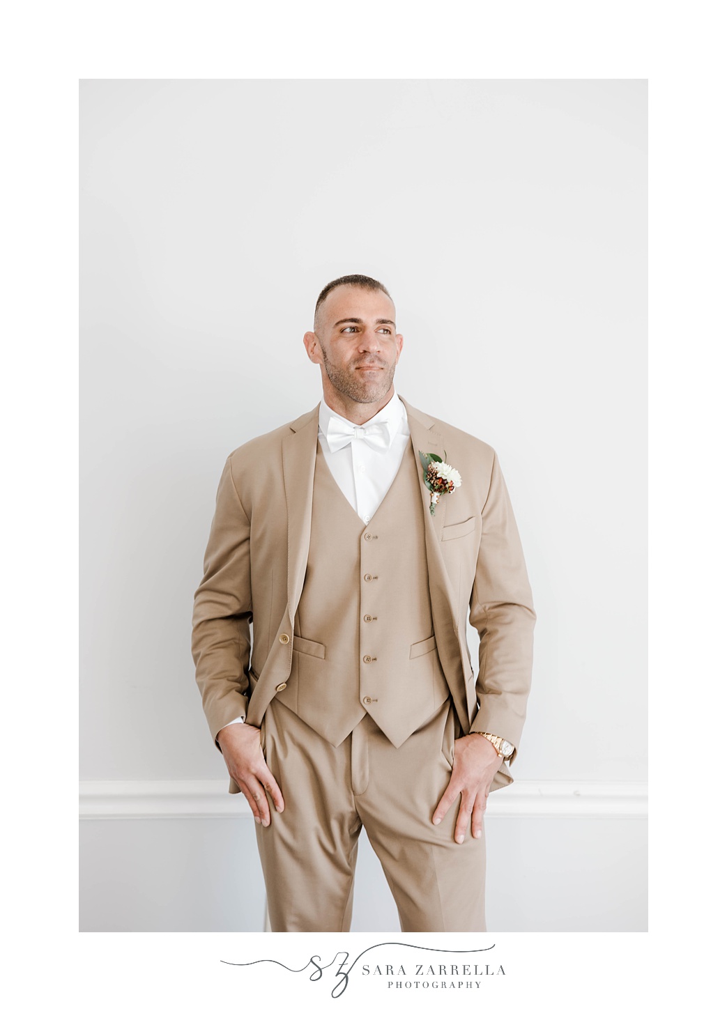 groom stands in tan suit during Newport RI wedding