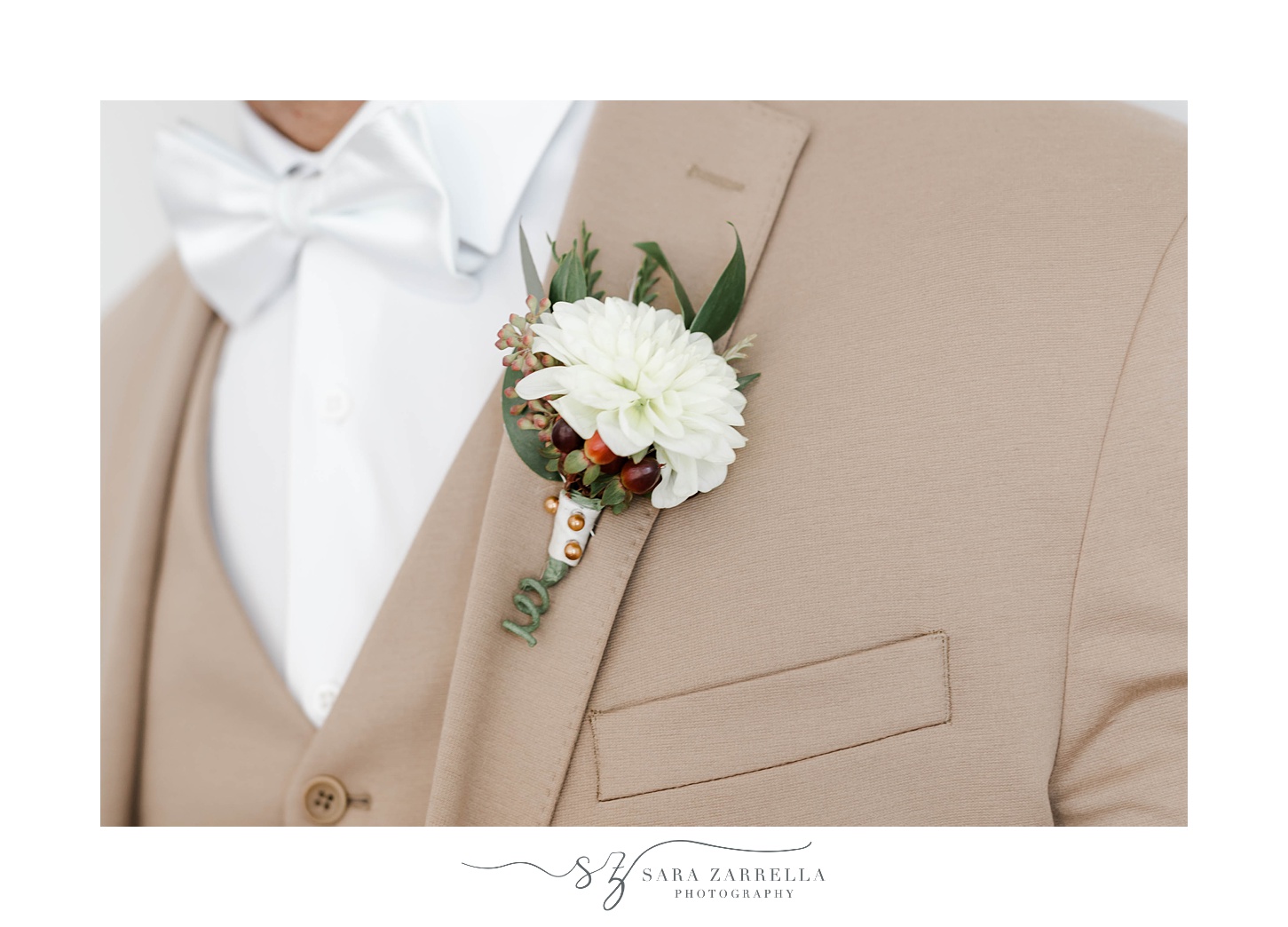 groom's white boutonnière on tan suit