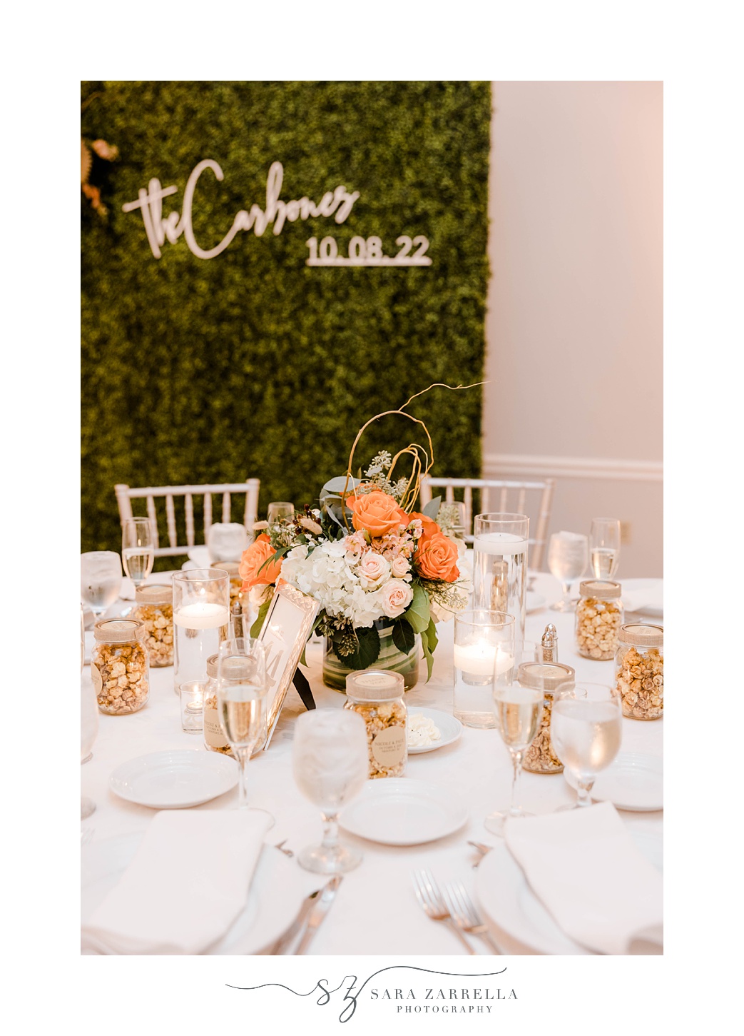 wedding reception with greenery wall with orange and white flowers 