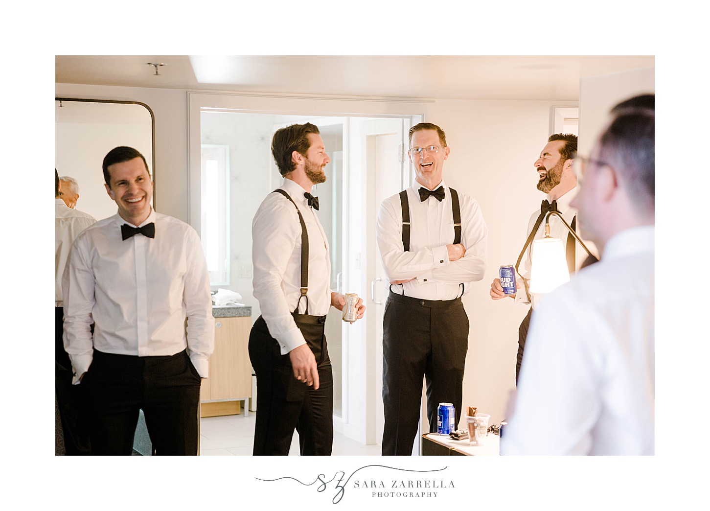 groom laughs with groomsmen in suspenders before RI wedding 
