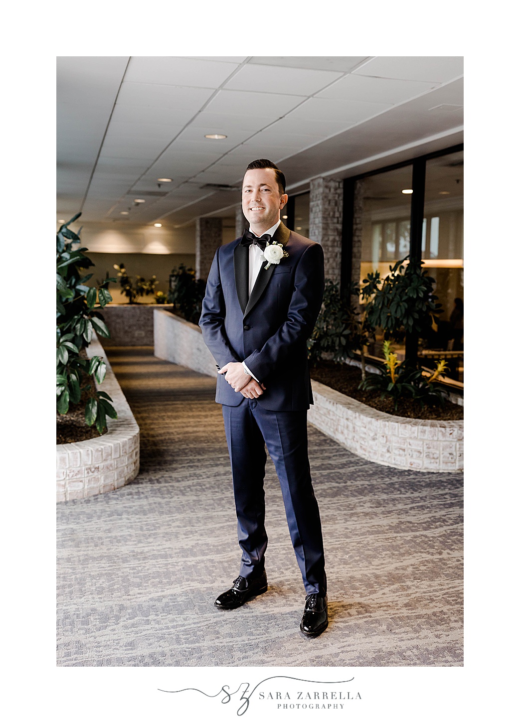 groom stands in lobby at Newport Harbor Island Resort for first look