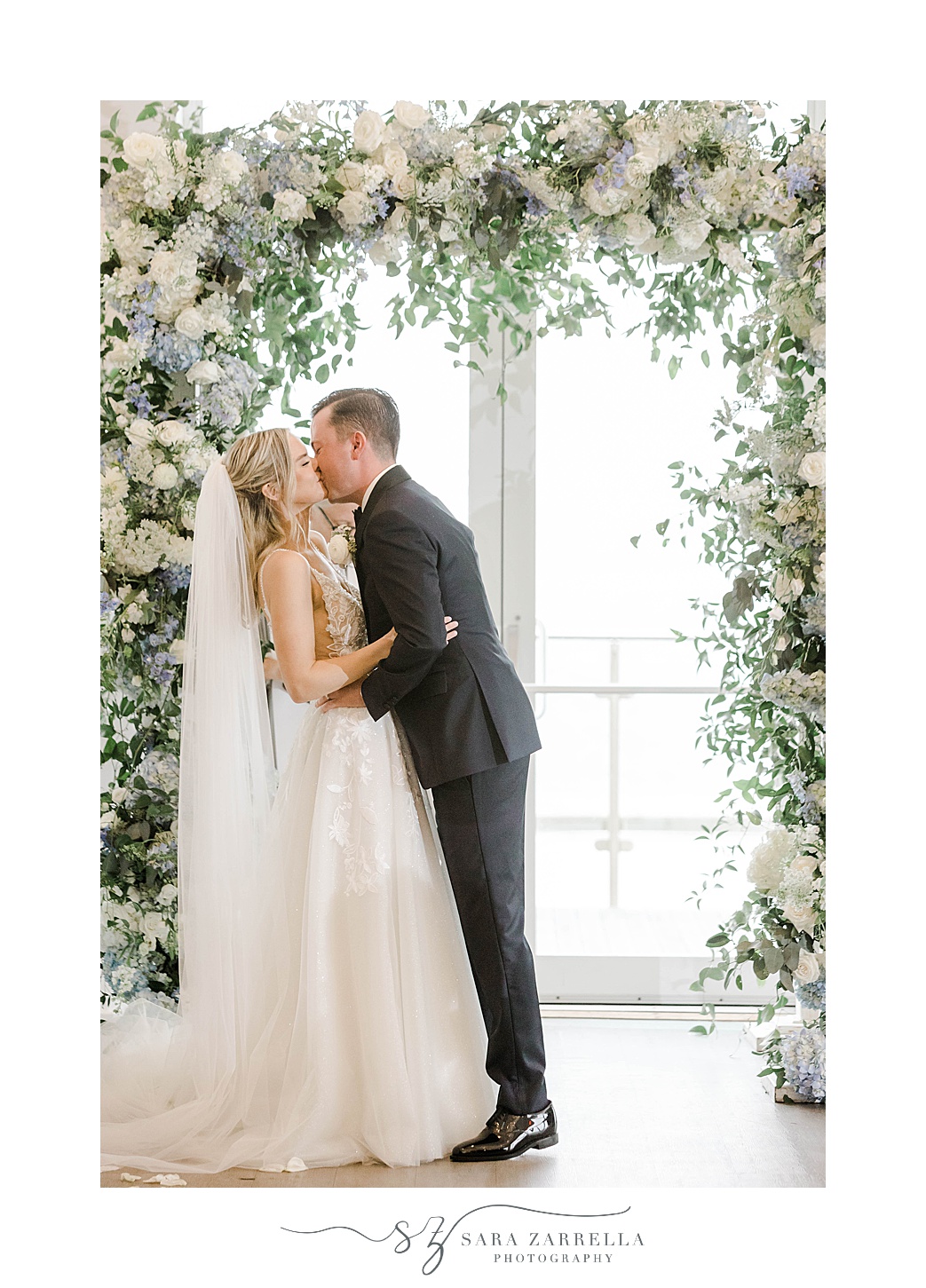 bride and groom kiss under floral arbor during ceremony at Newport Harbor Island Resort