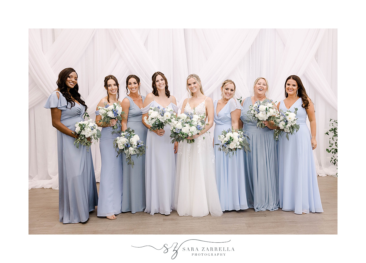 bride smiles with bridesmaids in pale blue gowns