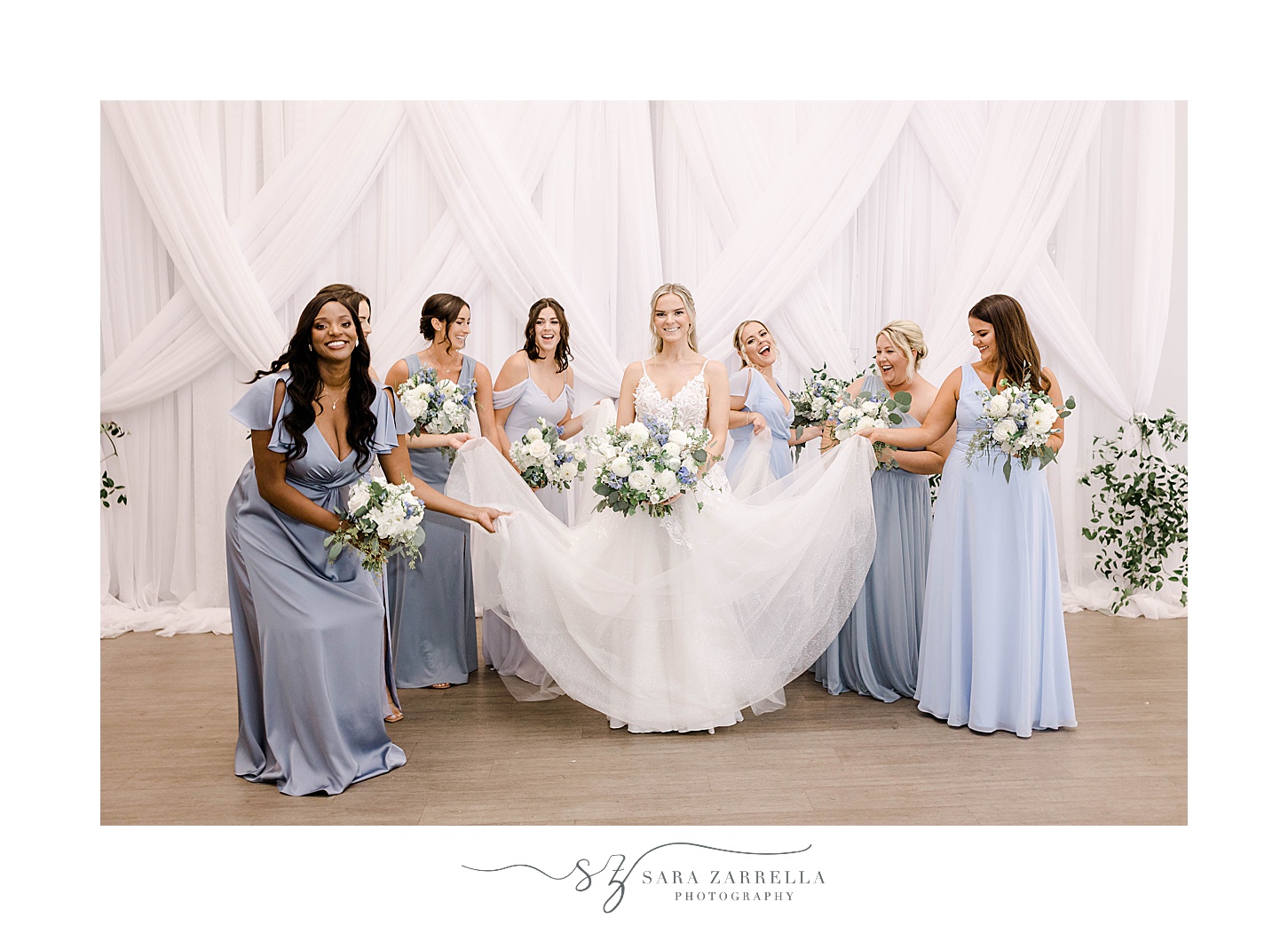 bridesmaids in pale blue gowns help bride with wedding dress
