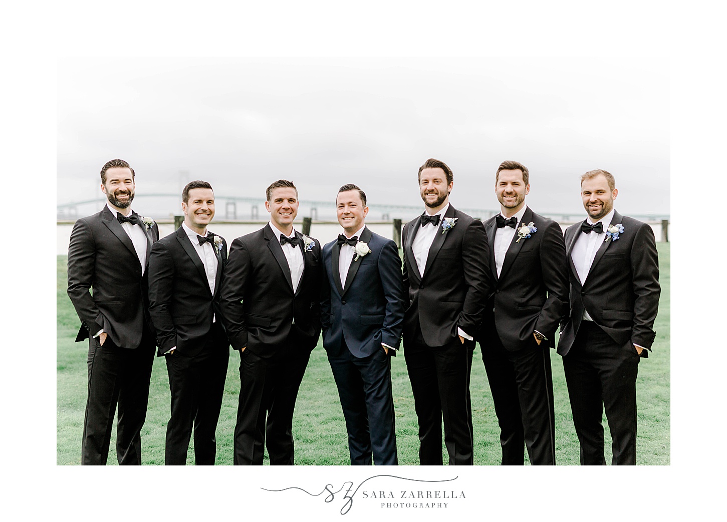 groom stands with groomsmen in navy and black suits in Newport RI