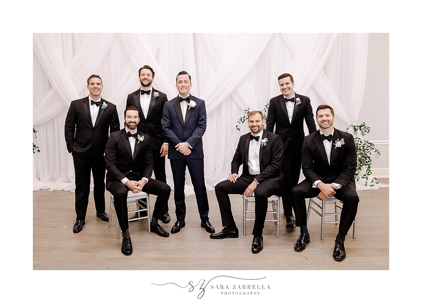 groom sits with groomsmen in navy suits in Newport Harbor Island Resort
