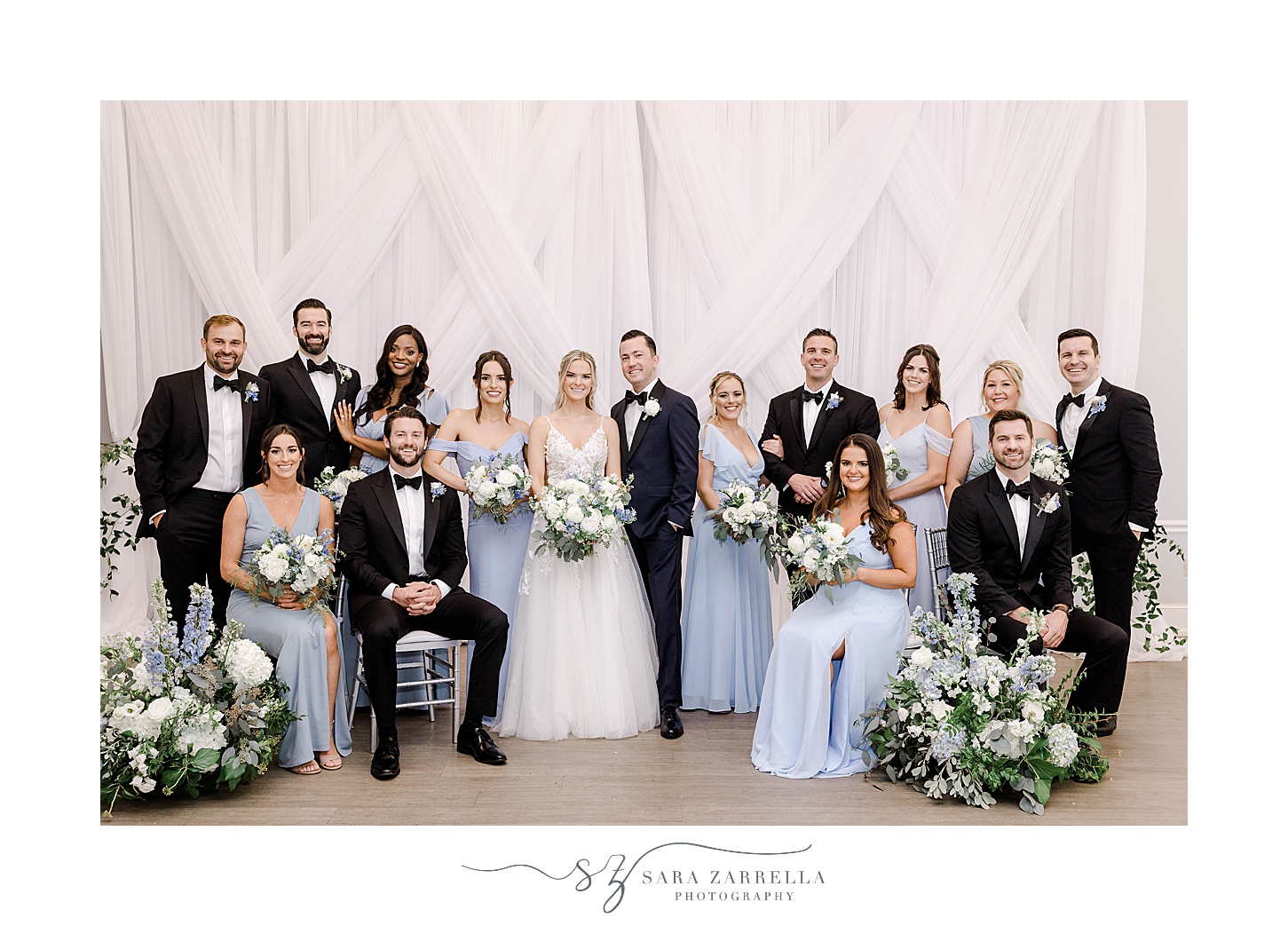 wedding party and bride and groom stand other by white drapes in Newport Harbor Island Resort