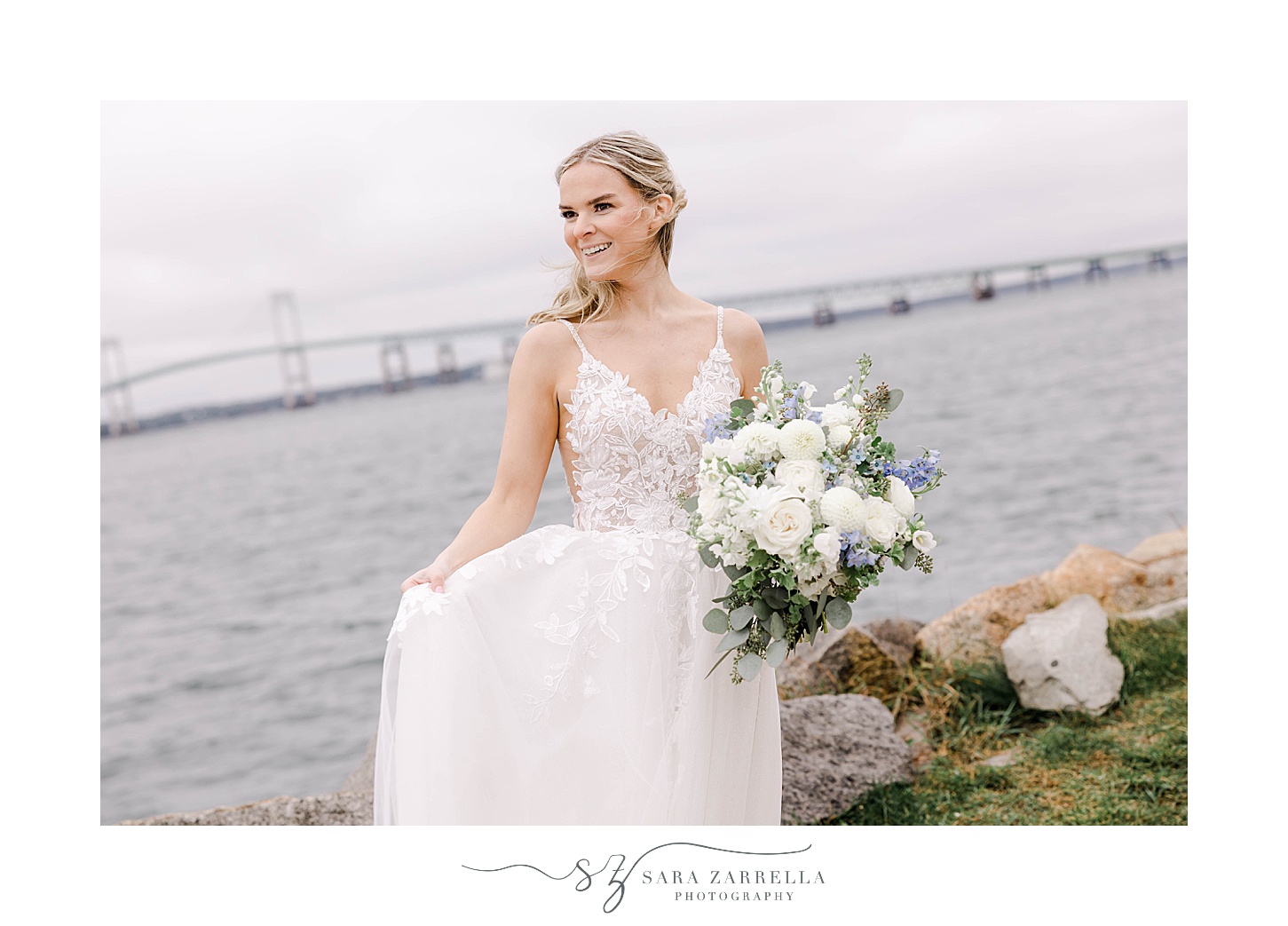bride shows off wedding gown with Newport Bridge behind her
