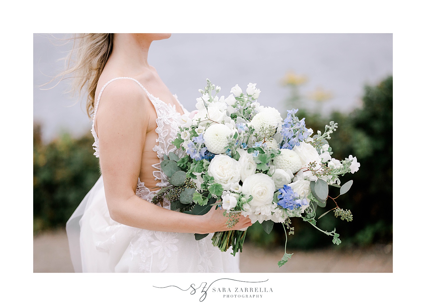 bride stands holding blue and white bouquet in Newport RI