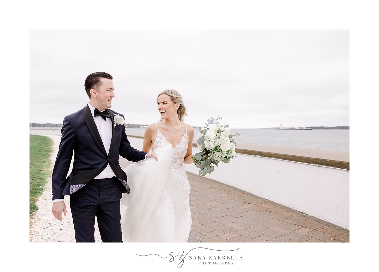 newlyweds laugh walking together on windy day in Newport RI