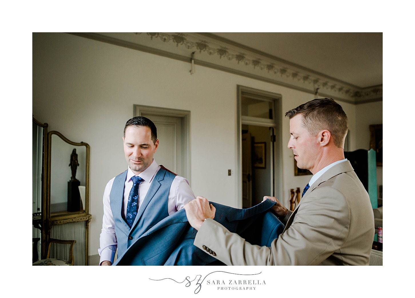 groom helps partner into jacket before Rosecliff Mansion wedding