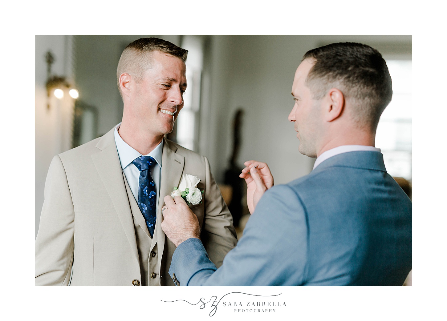 groom in blue suit adjusts boutonniere for partner  