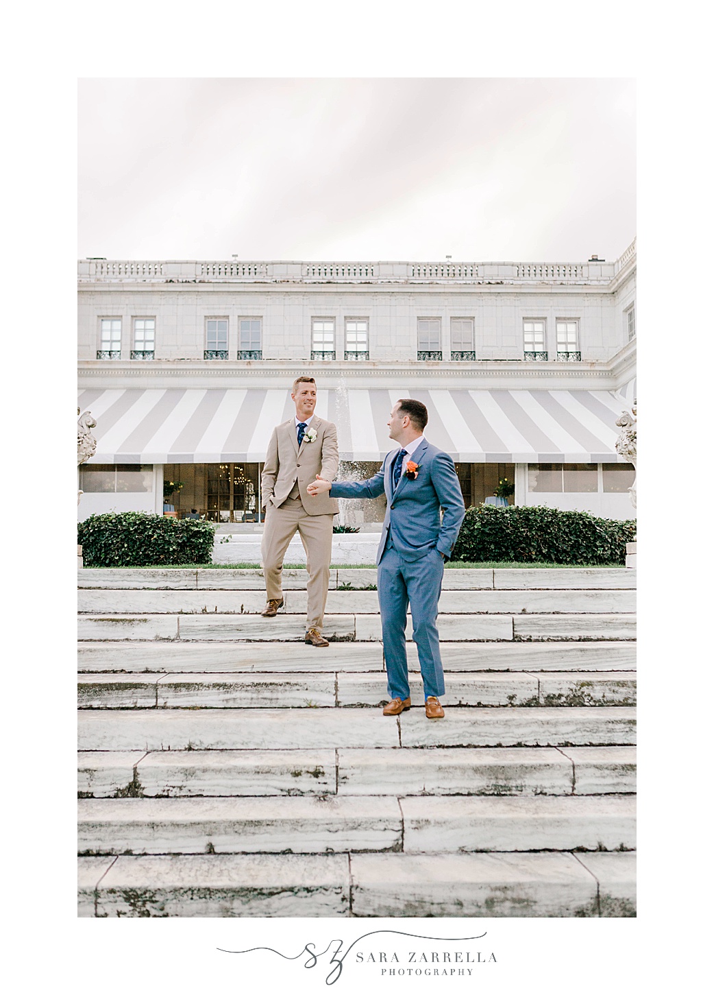 grooms hold hands walking down steps at Rosecliff Mansion