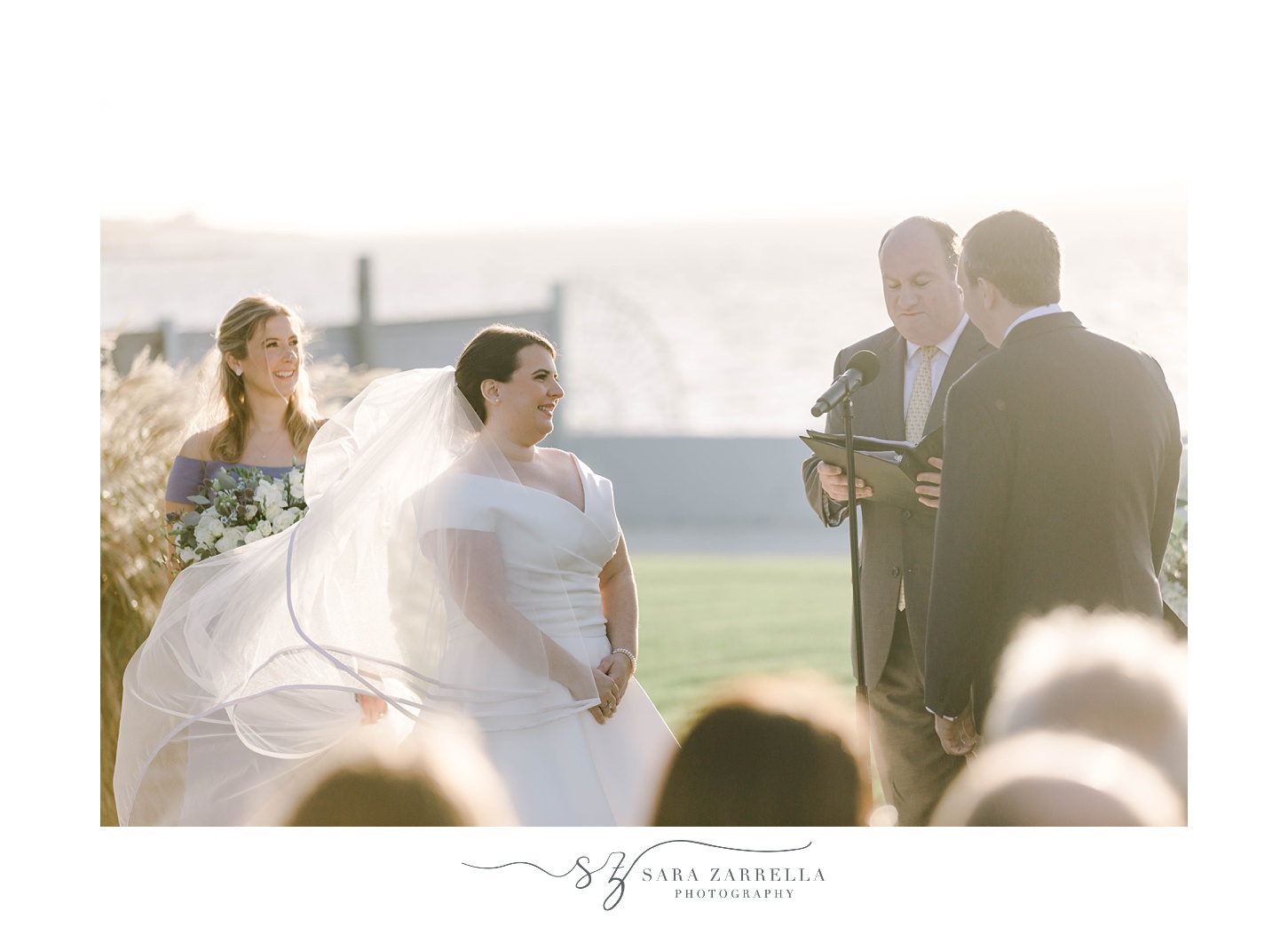 officiant speaks to bride and groom during ceremony on lawn at Belle Mer