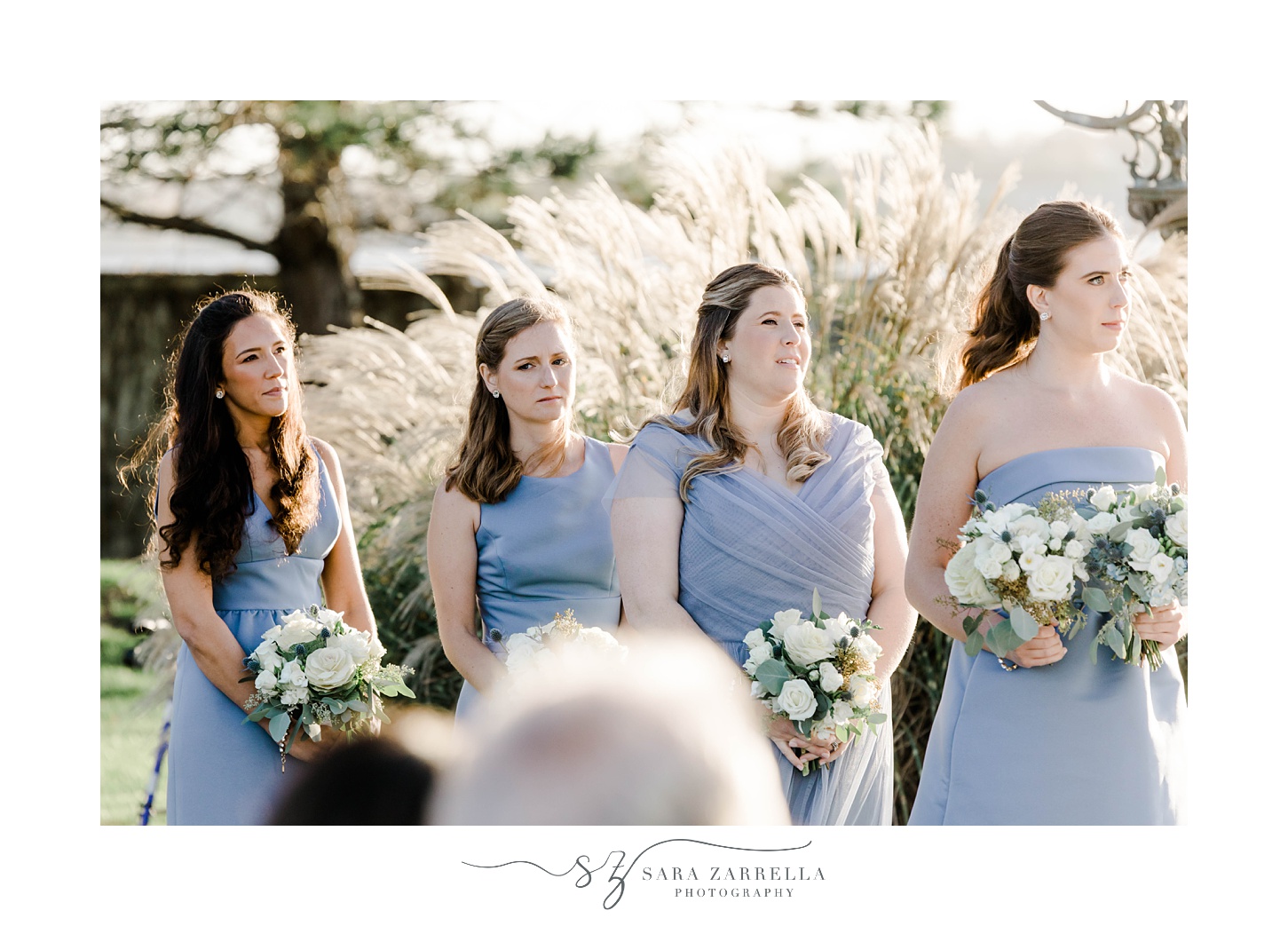 bridesmaids in pale blue gowns watch ceremony on lawn at Belle Mer