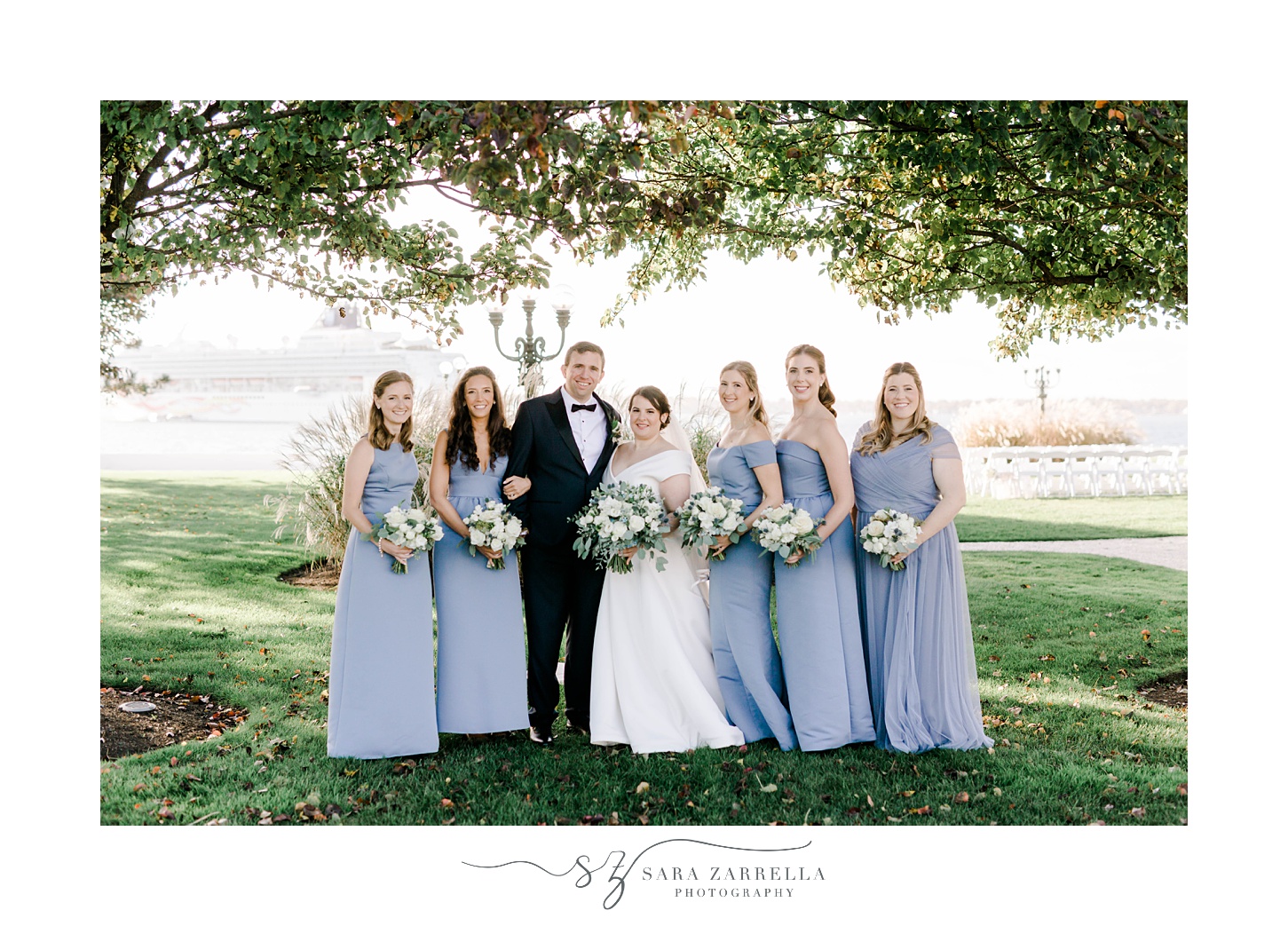 bride and groom stand with bridesmaids in light blue gowns in Rhode Island 