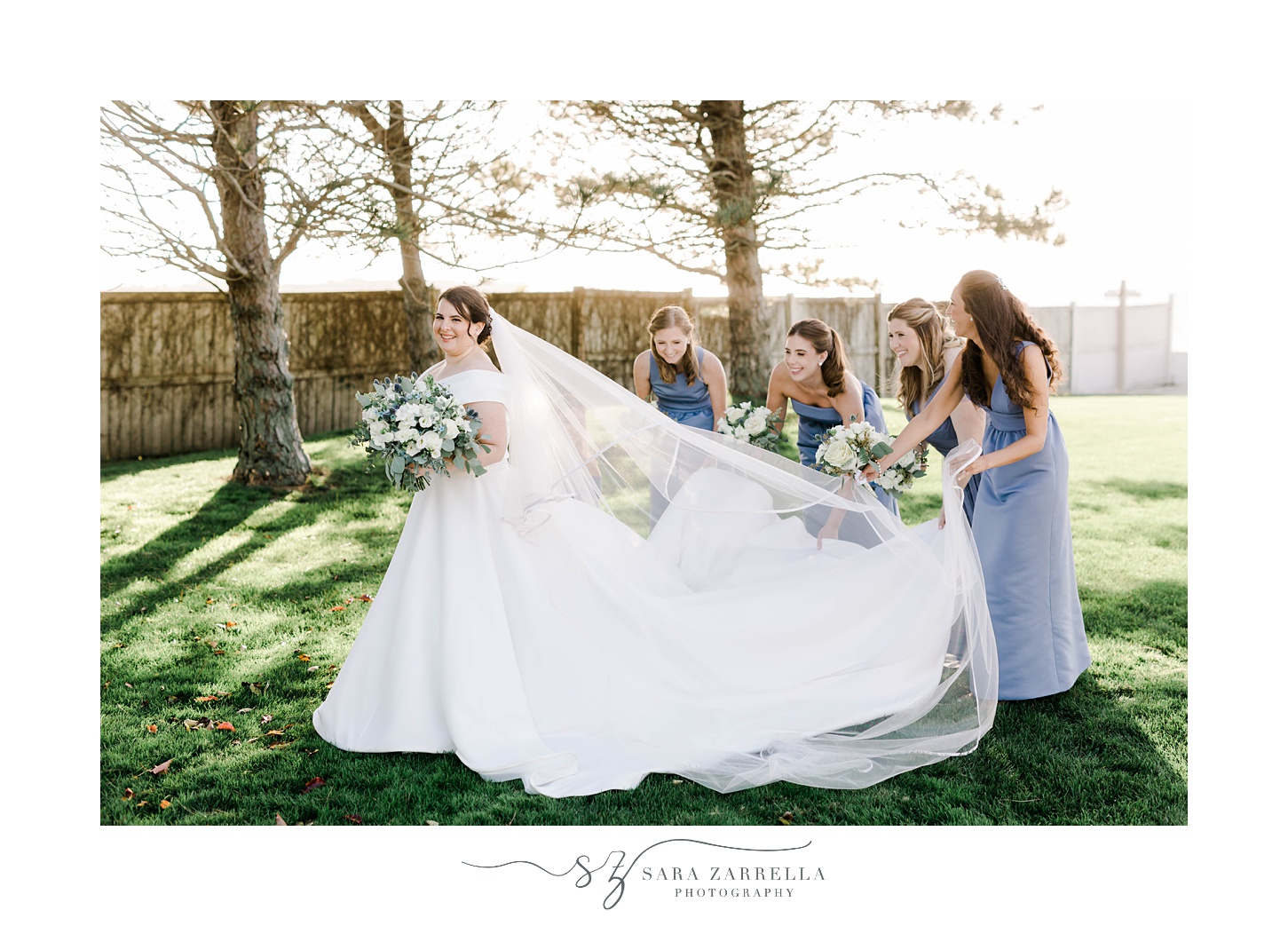 bridesmaids help adjust bride's veil on lawn at Belle Mer