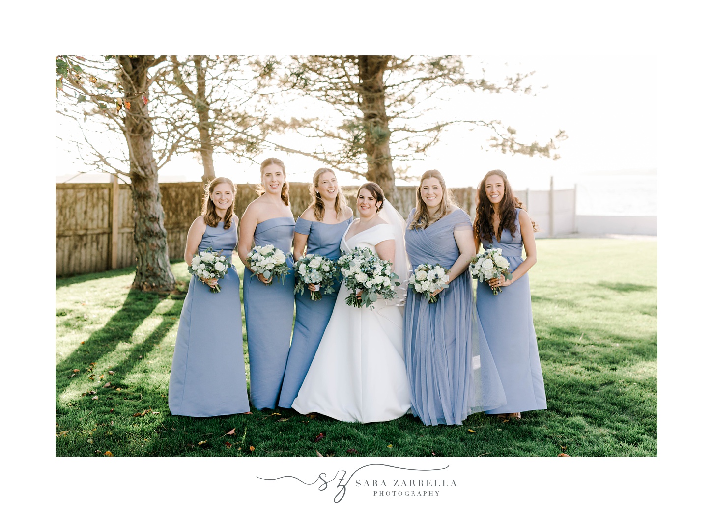 bride stands with bridesmaids in light blue gowns at Belle Mer