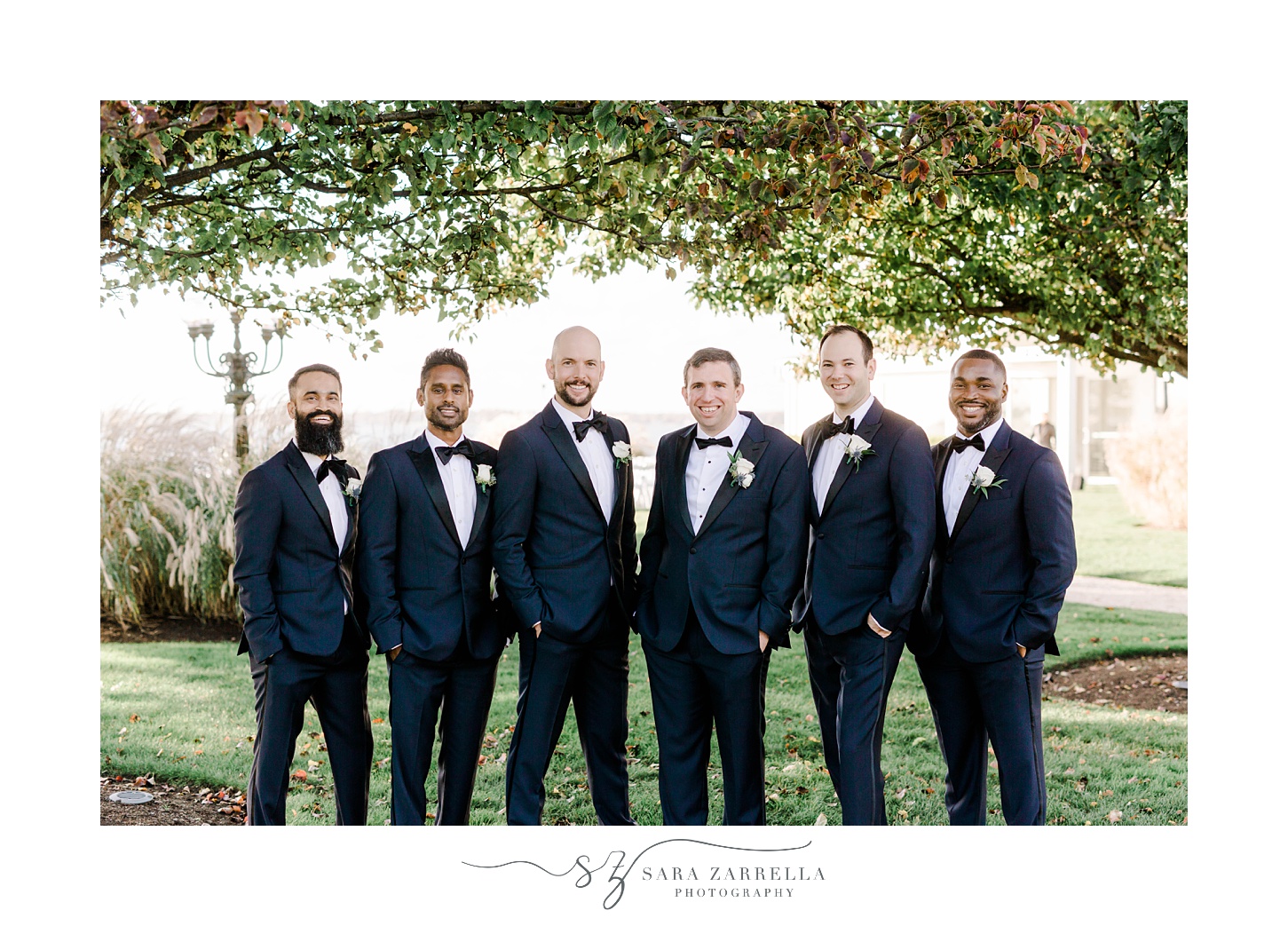 groom and groomsmen stand in suits with blue jackets 