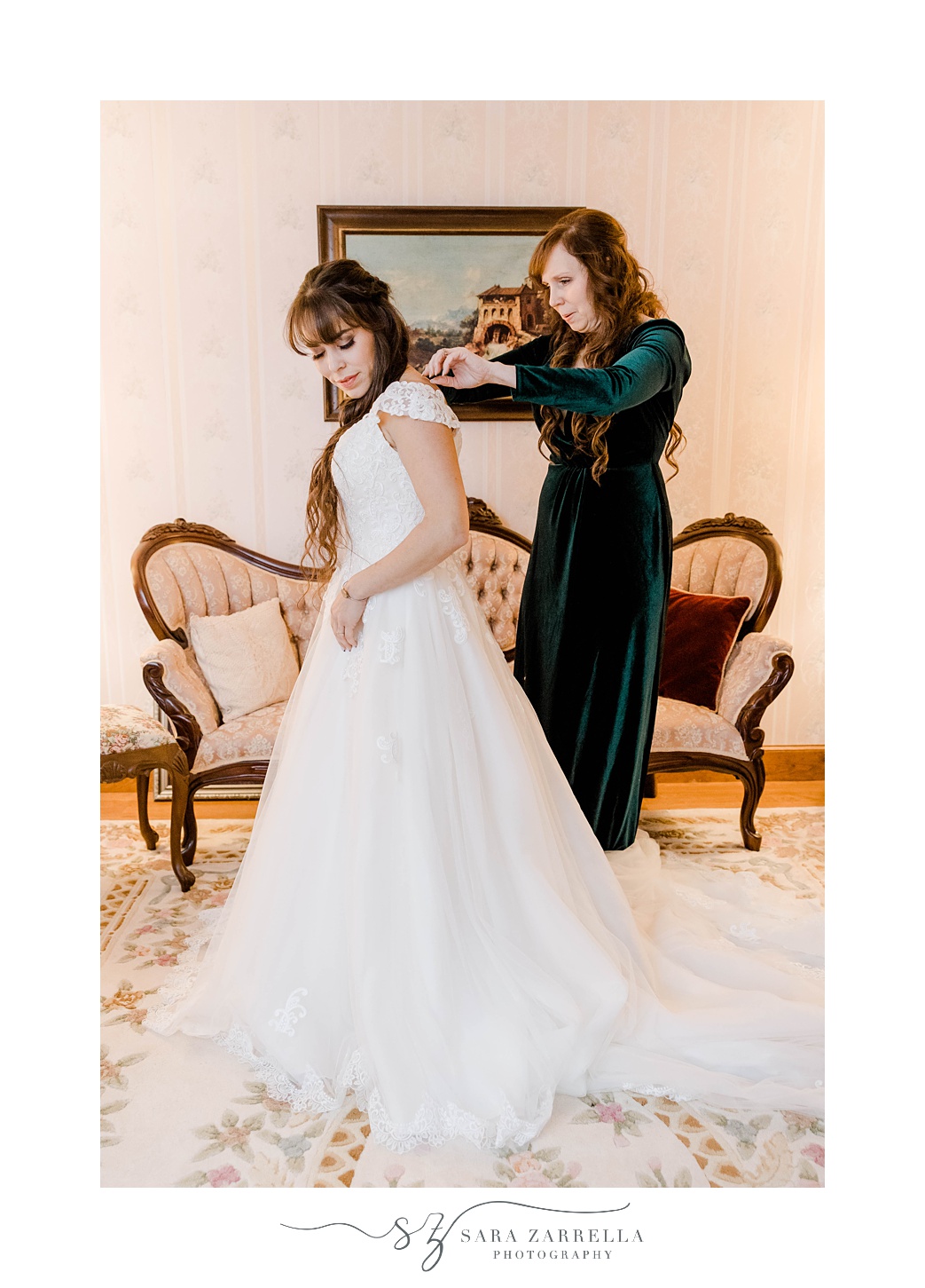 bride and bridesmaid get bride into wedding gown 